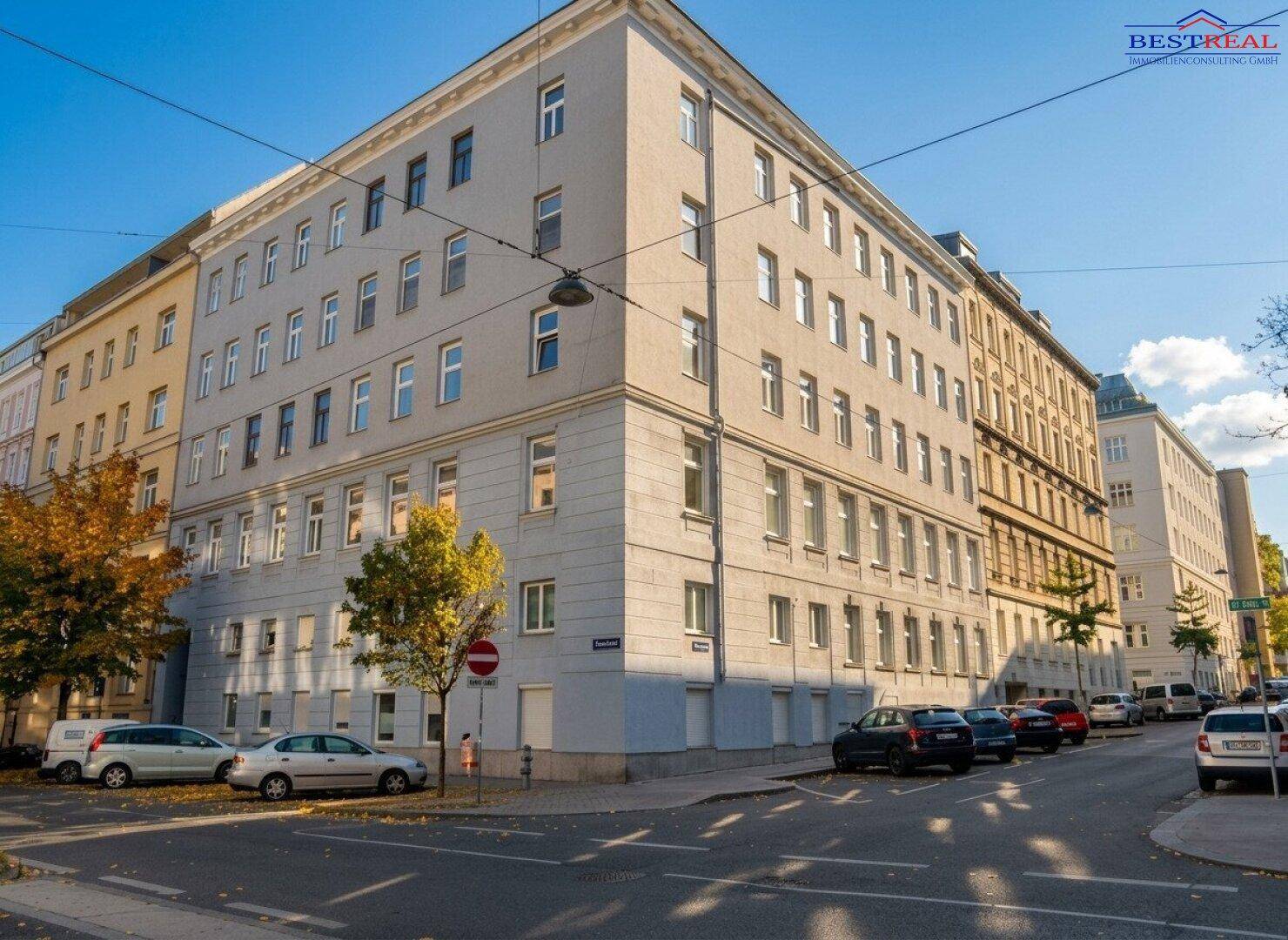 Historisches Mehrfamilienhaus an einer Straßenecke mit klassischer Architektur und vielen Fenstern.