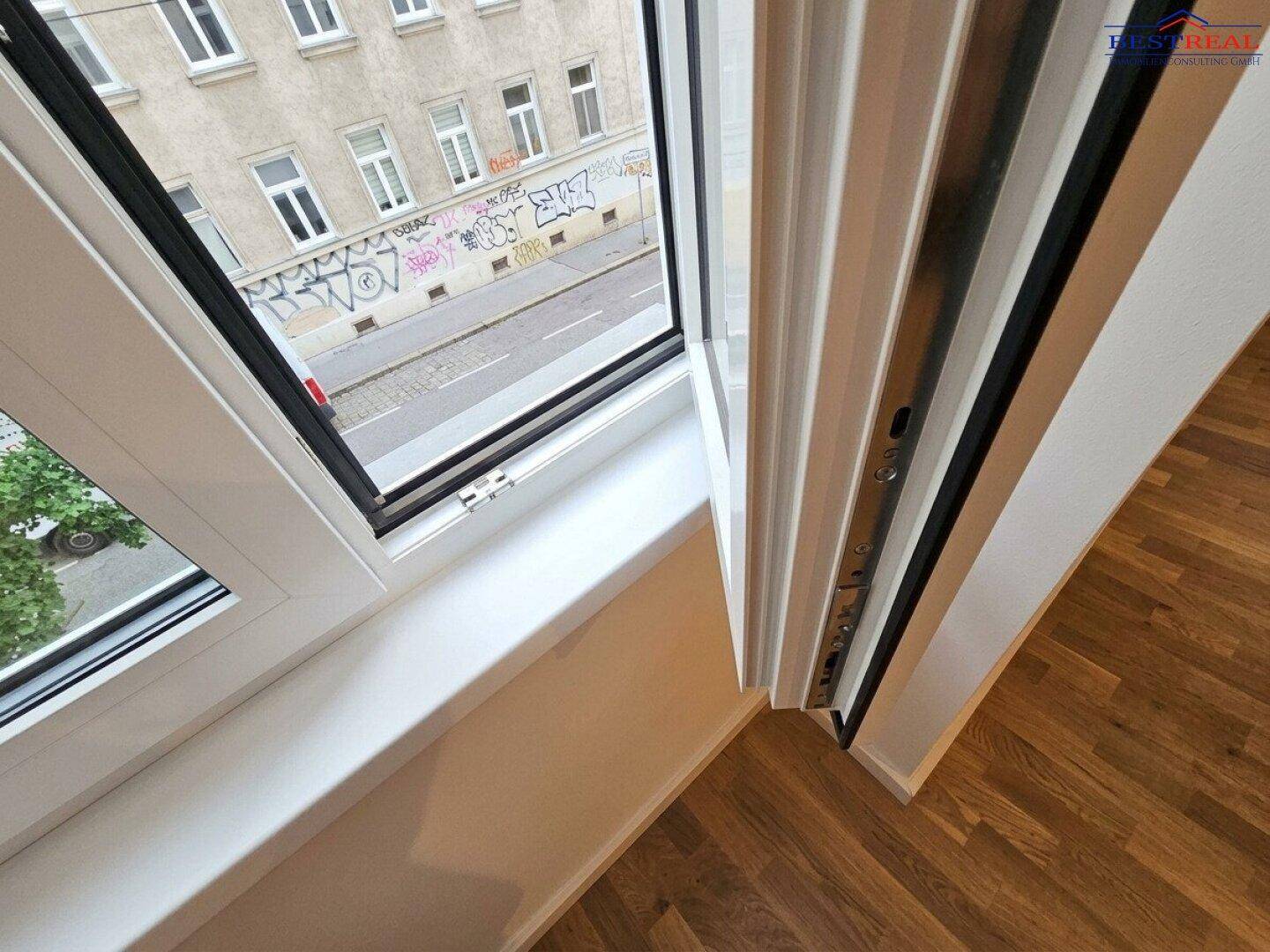 Geöffnetes Fenster mit Blick auf die Straße und die gegenüberliegenden Gebäude, sorgt für natürliches Licht.