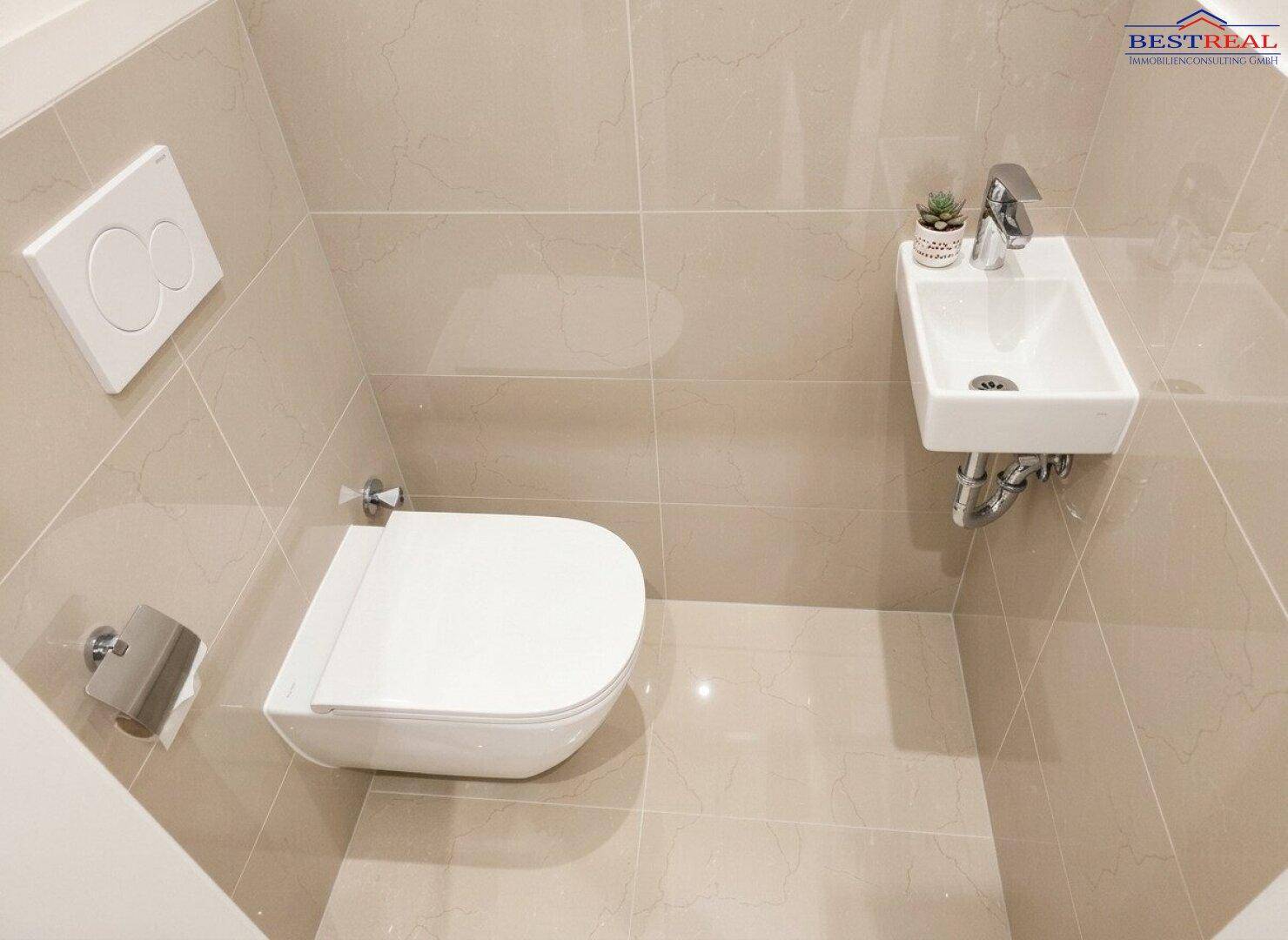 Kleines Gäste-WC mit wandhängender Toilette und Handwaschbecken, modern gefliest und sauber.