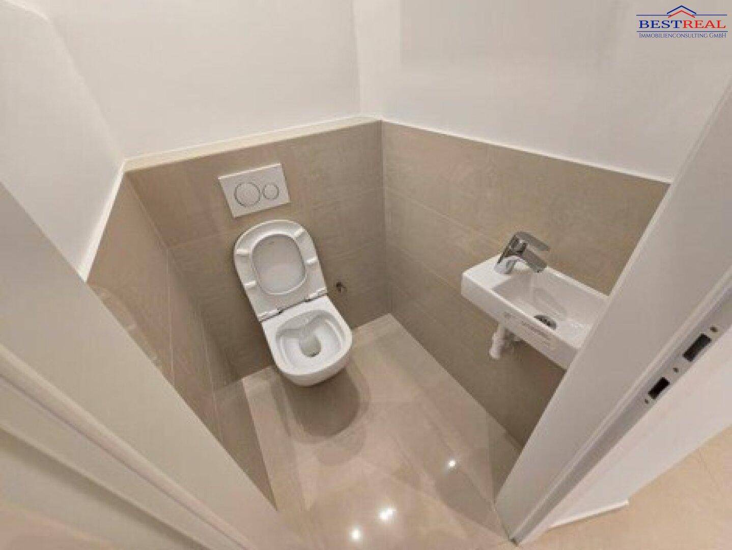 Kompaktes Gäste-WC mit Wand-WC und kleinem Waschbecken, modern gefliest.