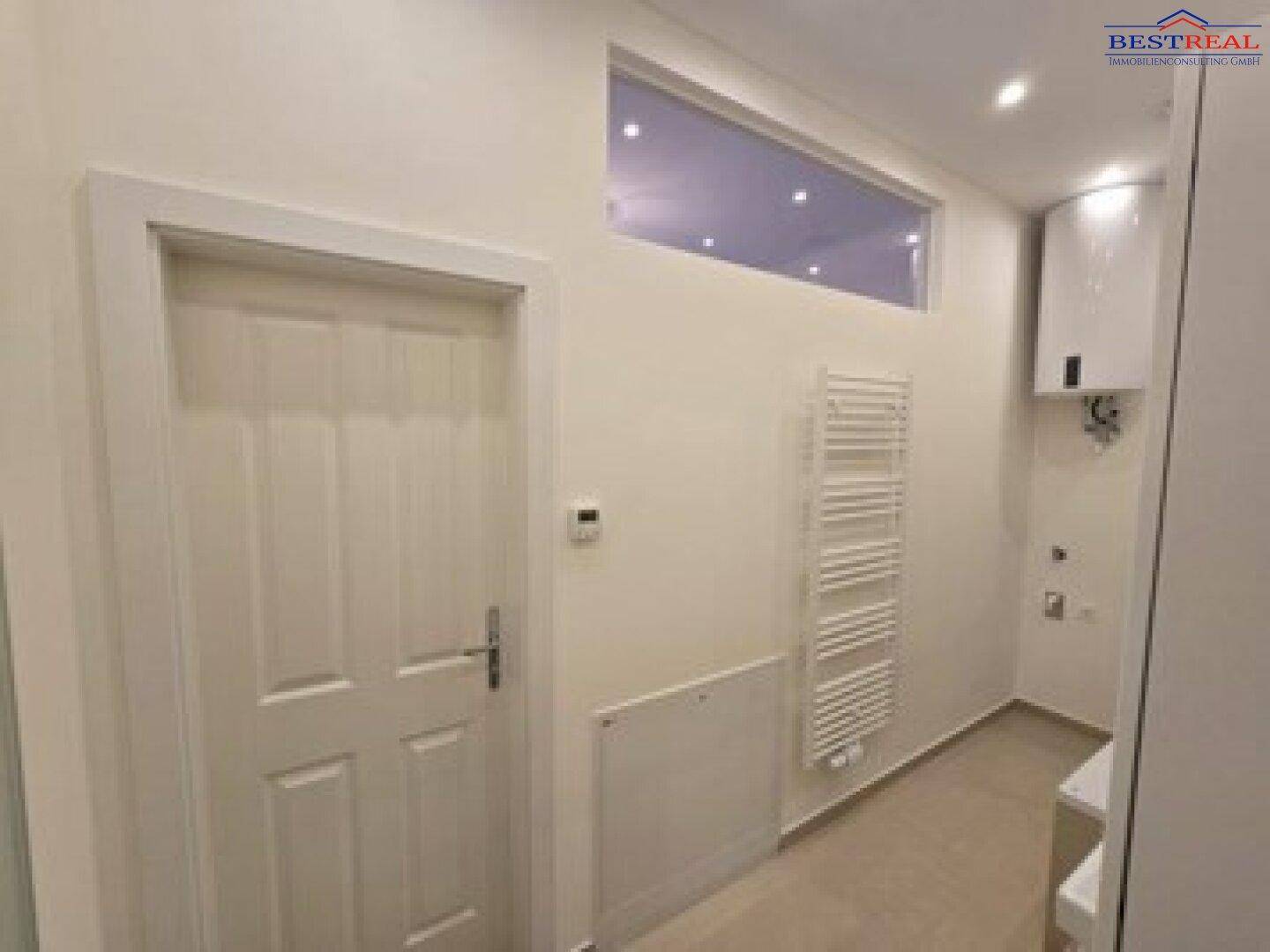 Modernes Badezimmer mit Handtuchheizkörper, Warmwasserbereiter und Oberlichtfenster.