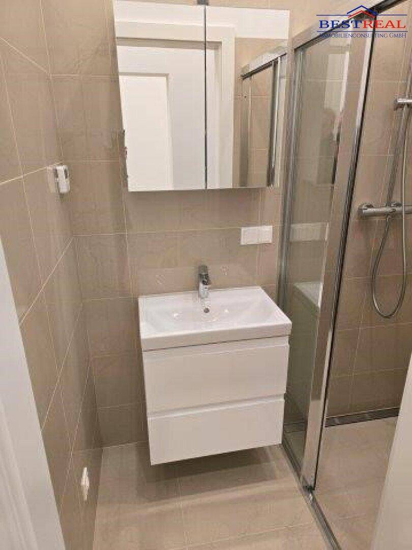 Modernes Badezimmer mit Duschkabine, Waschbeckenunterschrank und Spiegelschrank.