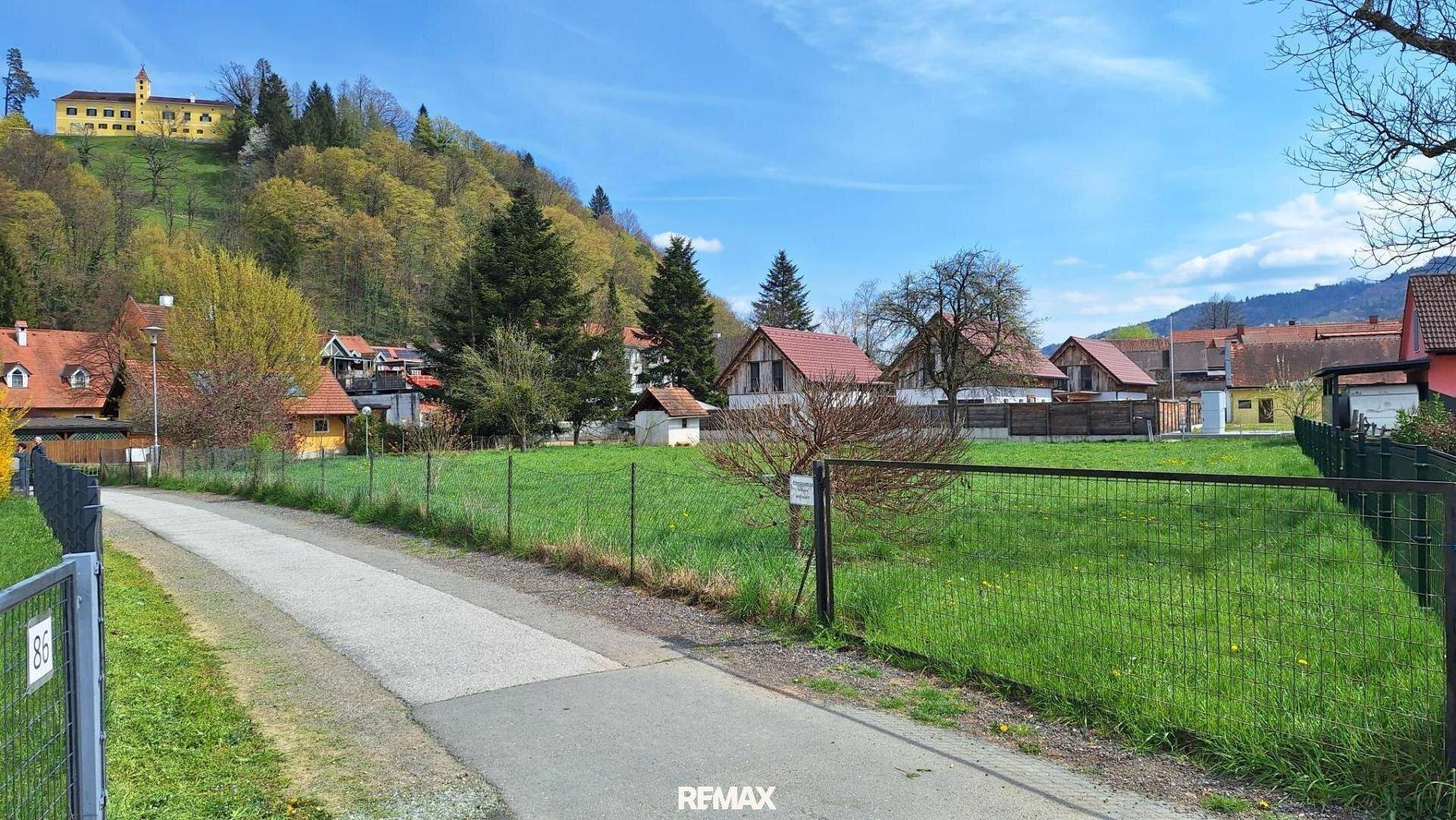 Grundstück mit Zufahrtsweg und weitem Blick auf die ländliche Umgebung und historische Gebäude.