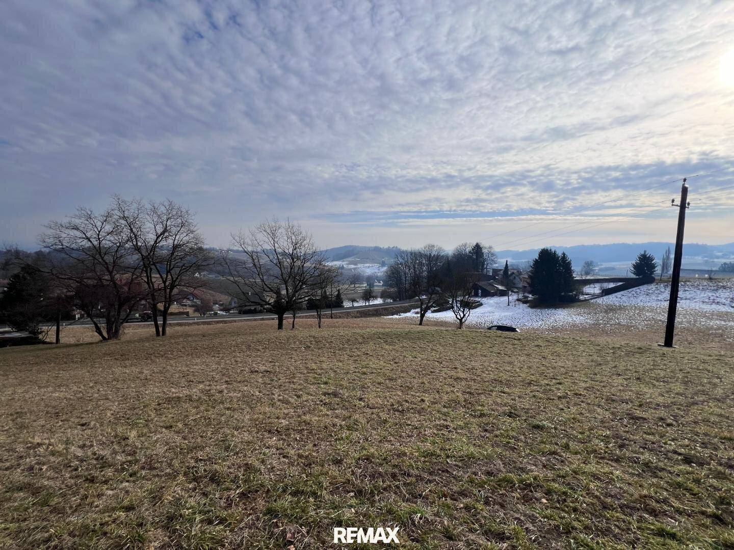 Weitläufiges Wiesengrundstück unter einem bewölkten Himmel mit Blick auf die ländliche Umgebung.