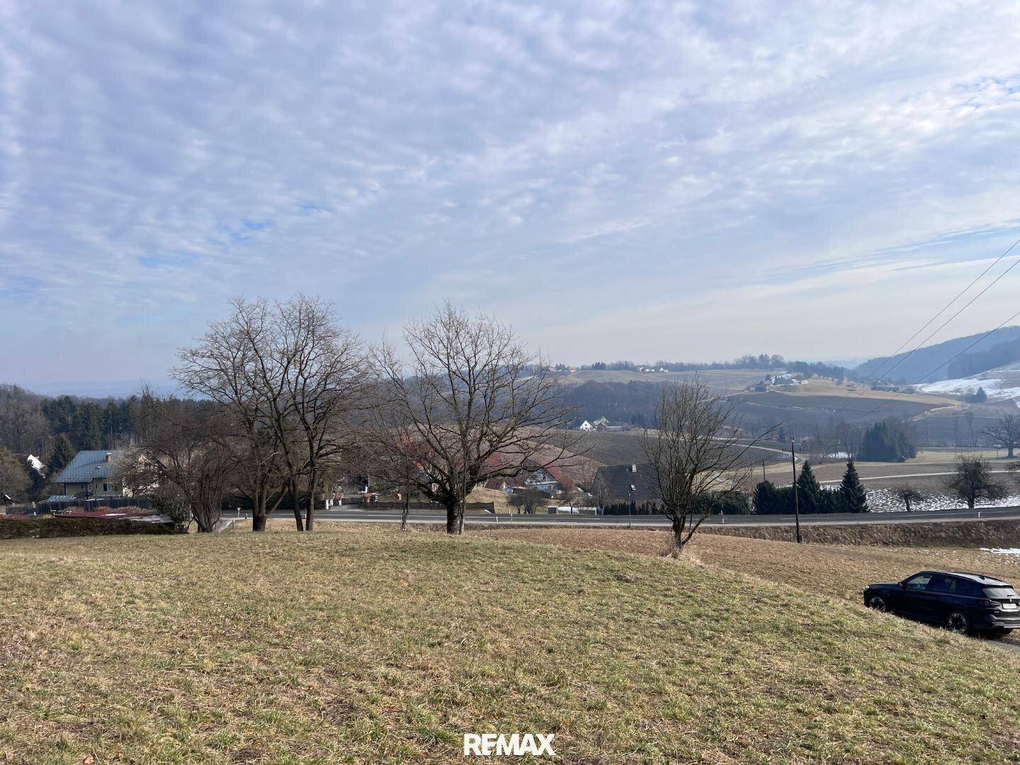 Weitläufiges Wiesengrundstück mit Fernblick auf die hügelige Landschaft und die umliegenden Ortschaften.