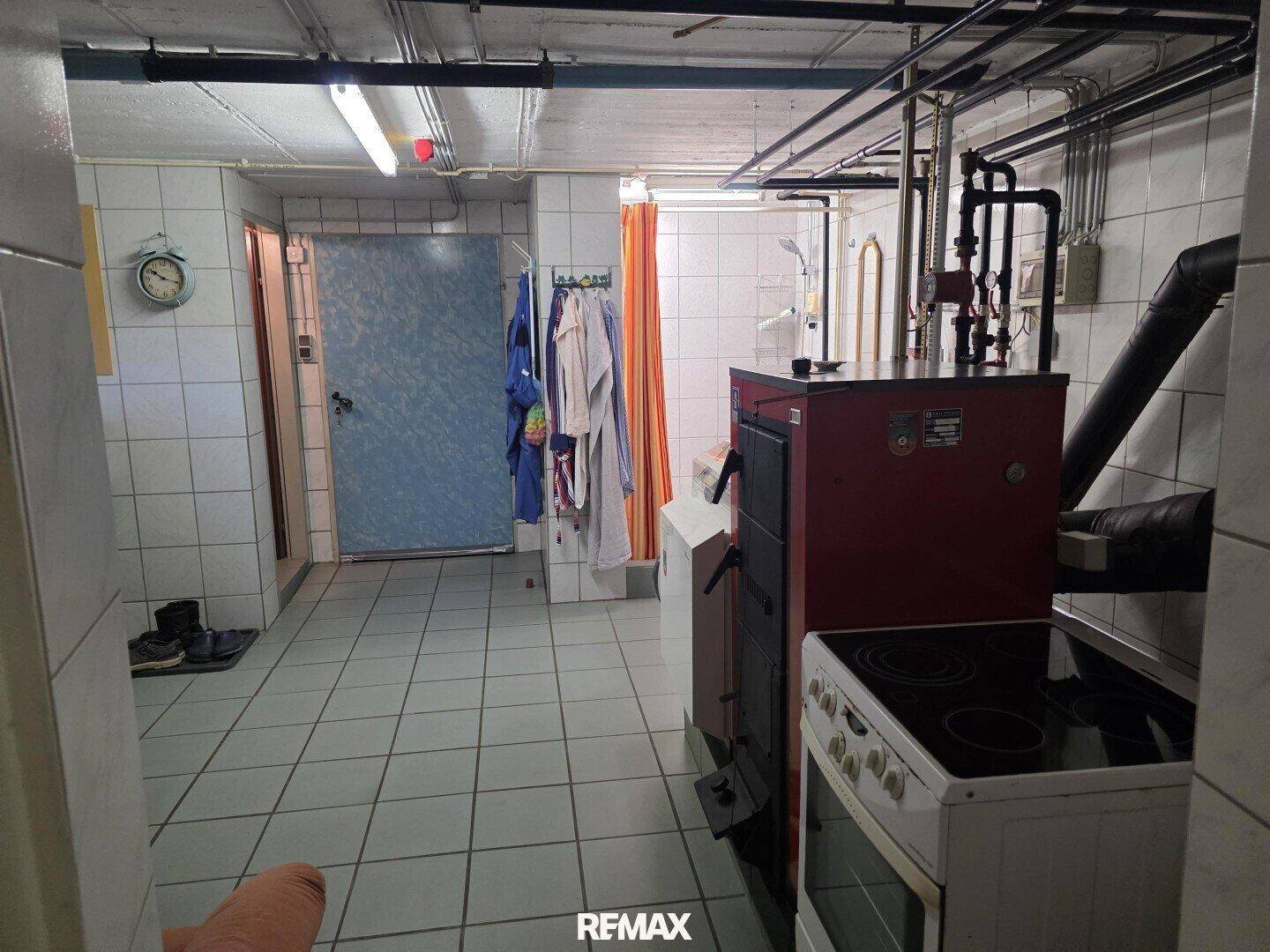 Kellerraum mit Heizkessel, Waschmaschine und weiteren Geräten, funktional gefliest.