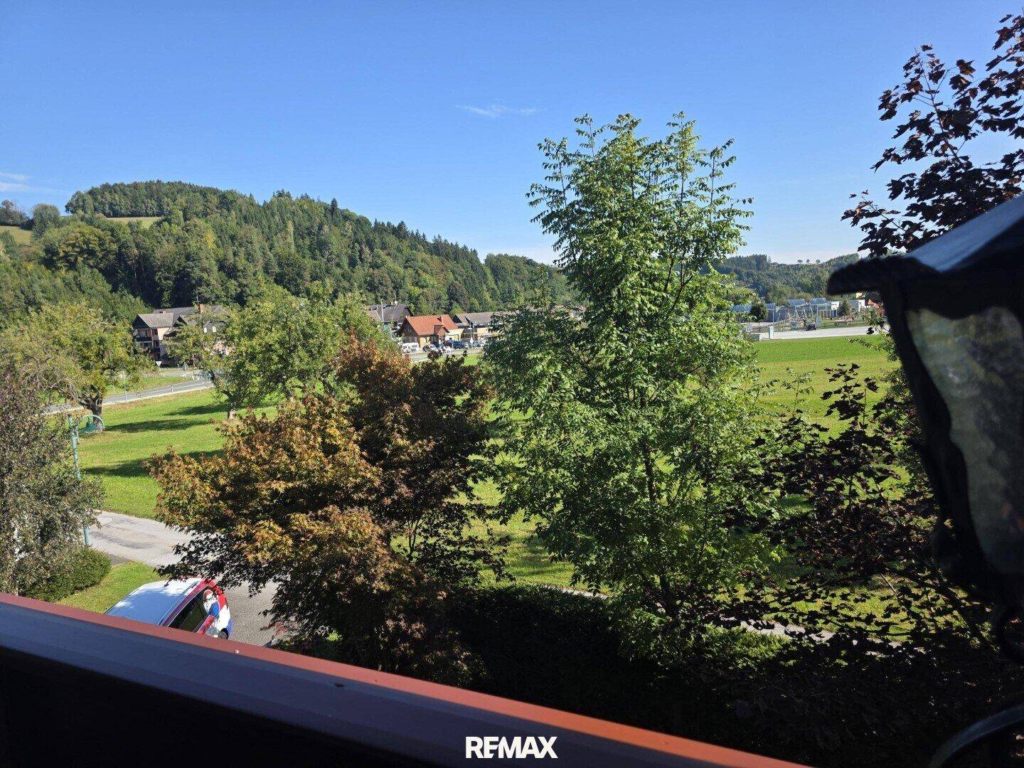 Weitläufiger Blick vom Balkon auf grüne Hügel, Bäume und die umliegende Landschaft.