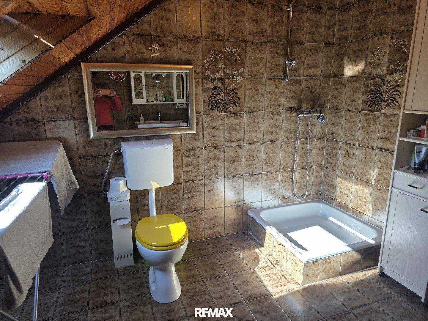 Badezimmer im Dachgeschoss mit schräger Decke, Fliesenboden und Badewanne.