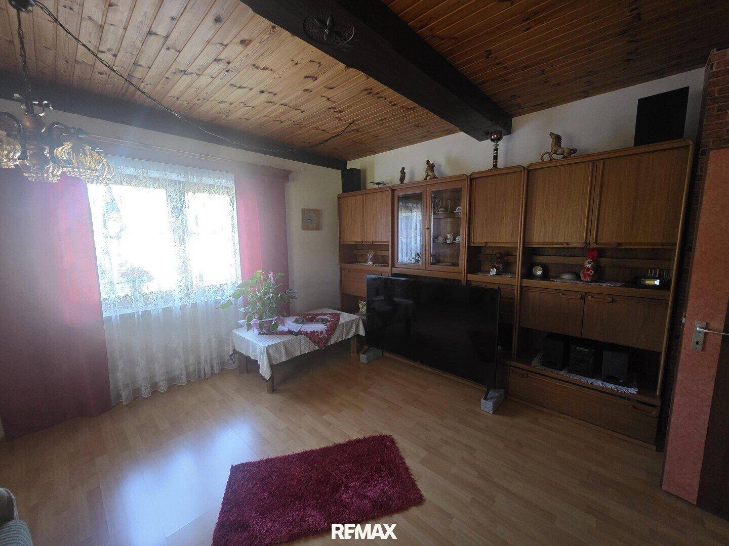 Wohnzimmer mit Holzdecke, Laminatboden und traditionellen Holzschränken.