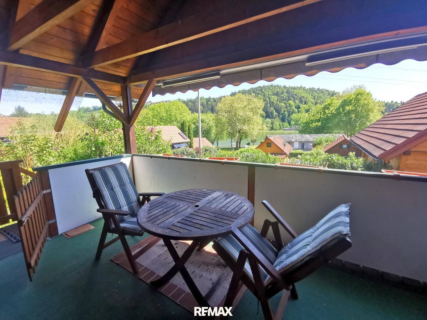 Überdachter Balkon mit Holztisch und Stühlen, ideal für entspannte Stunden im Freien.