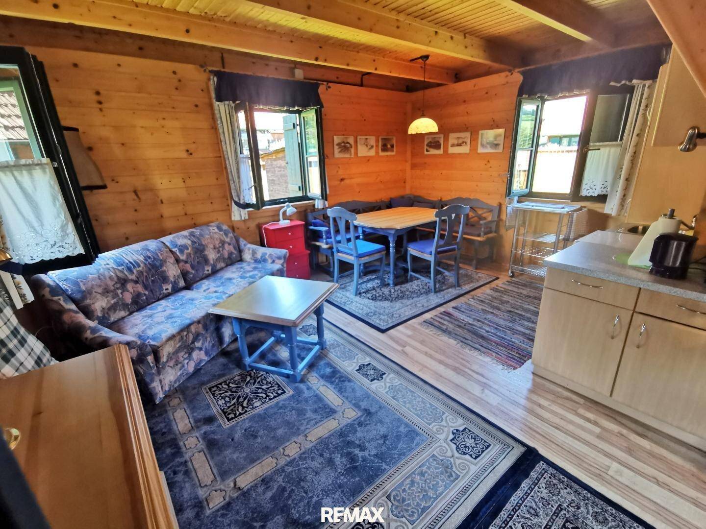 Gemütlicher Wohn- und Essbereich mit Holzvertäfelung, Teppichen und traditionellen Möbeln.