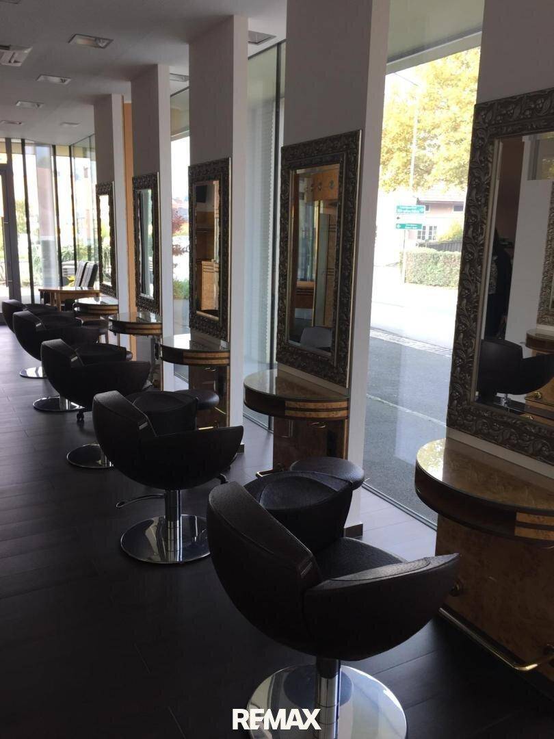 Reihe von Stylingplätzen in einem Friseursalon mit großen Spiegeln und Blick auf die Straße durch die Fenster.