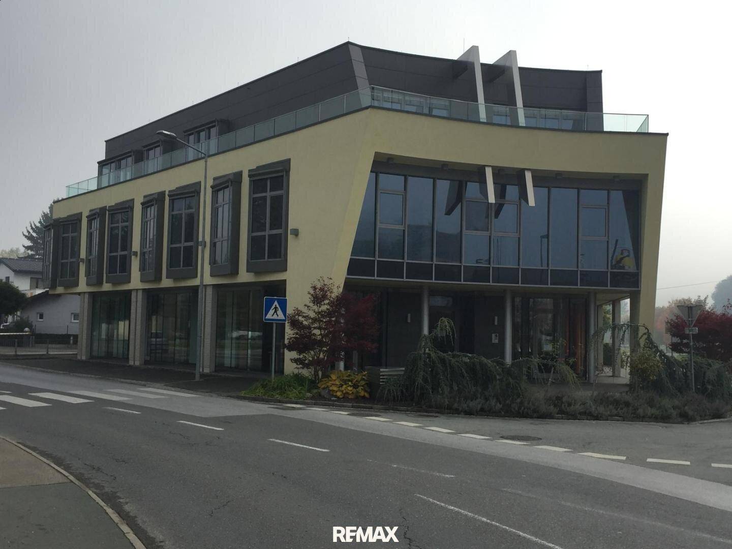 Ansicht des modernen Geschäftsgebäudes von der Straße aus mit großen Fensterfronten und einem Zebrastreifen davor.