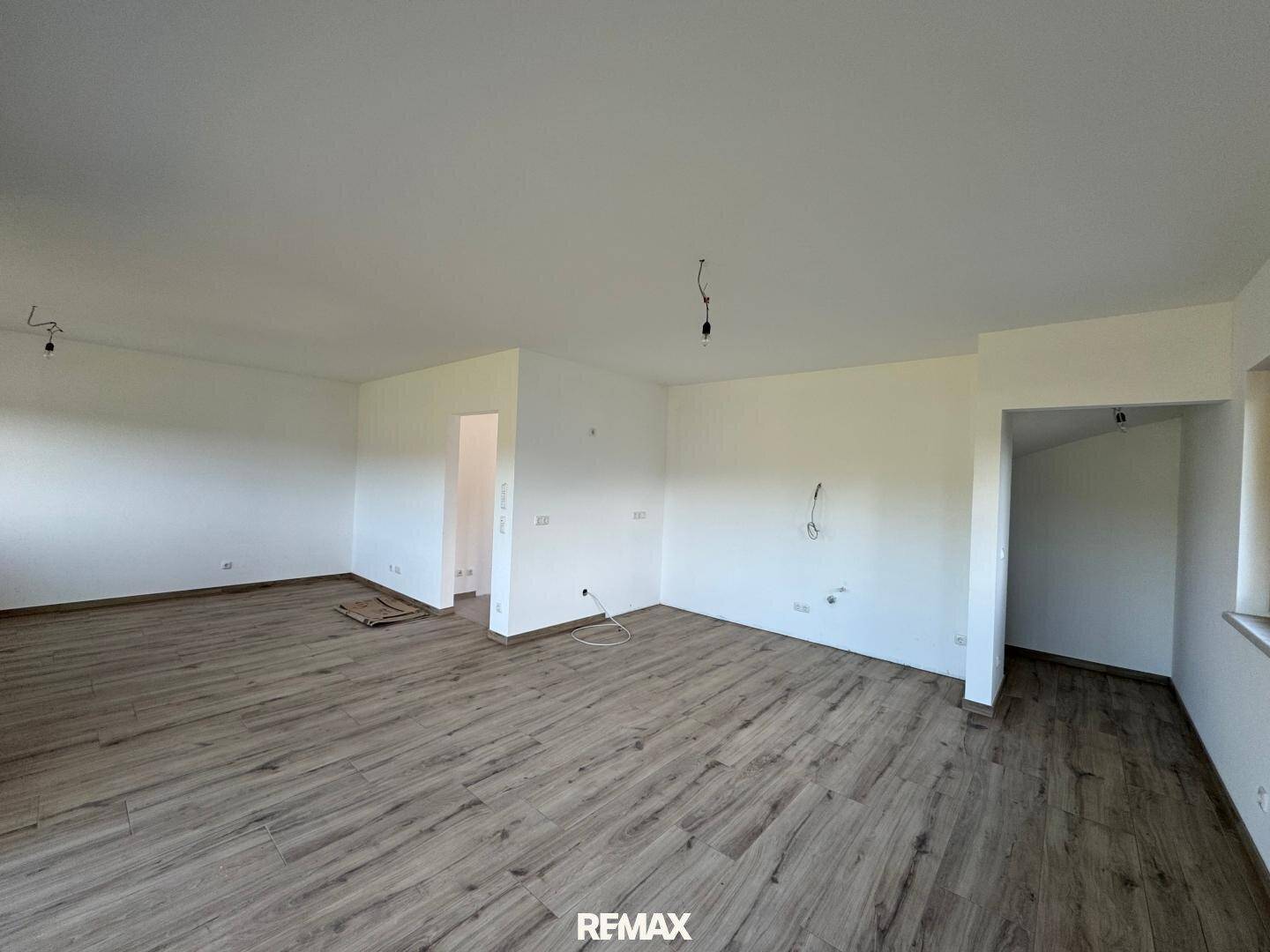 Heller, unmöblierter Wohnraum im Neubau mit Laminatboden und viel Tageslicht.