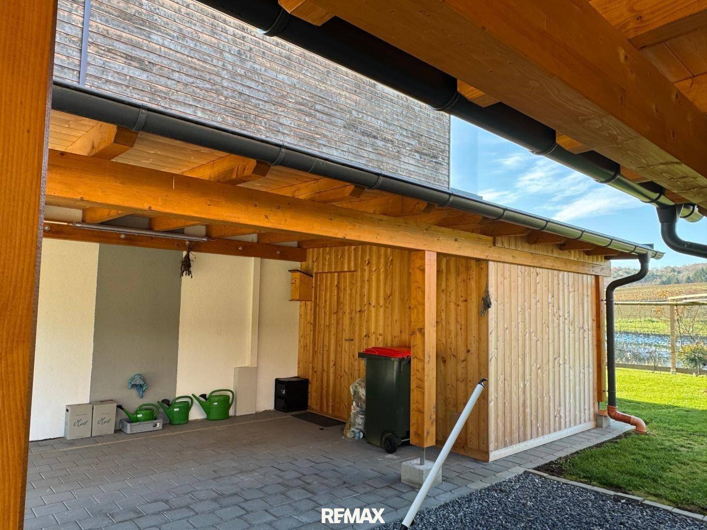 Geräumiger Holzcarport mit integriertem Abstellraum und Blick auf die ländliche Umgebung.