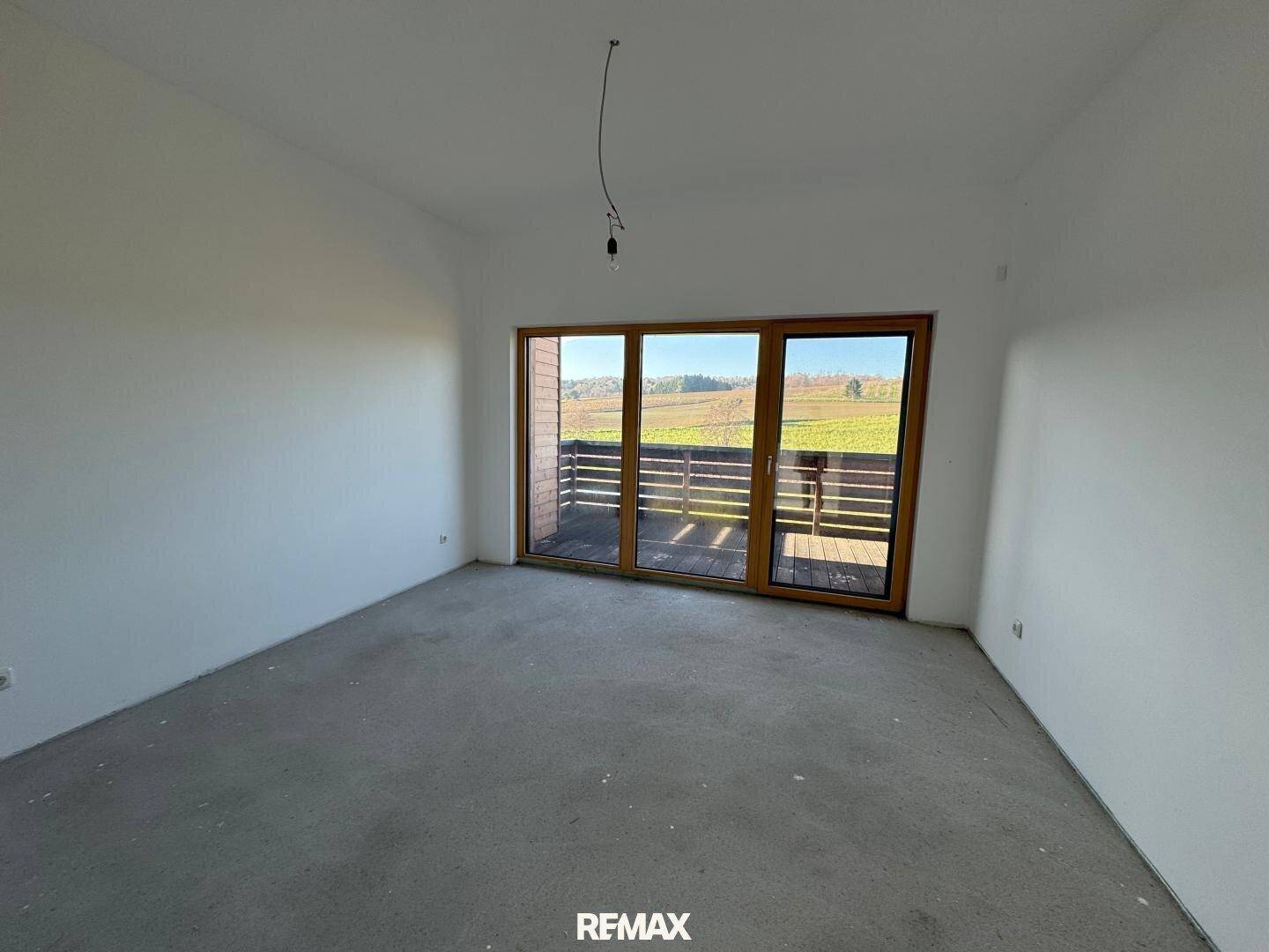 Heller Raum im Rohbau mit großer Balkontür und weitem Blick über die Landschaft.