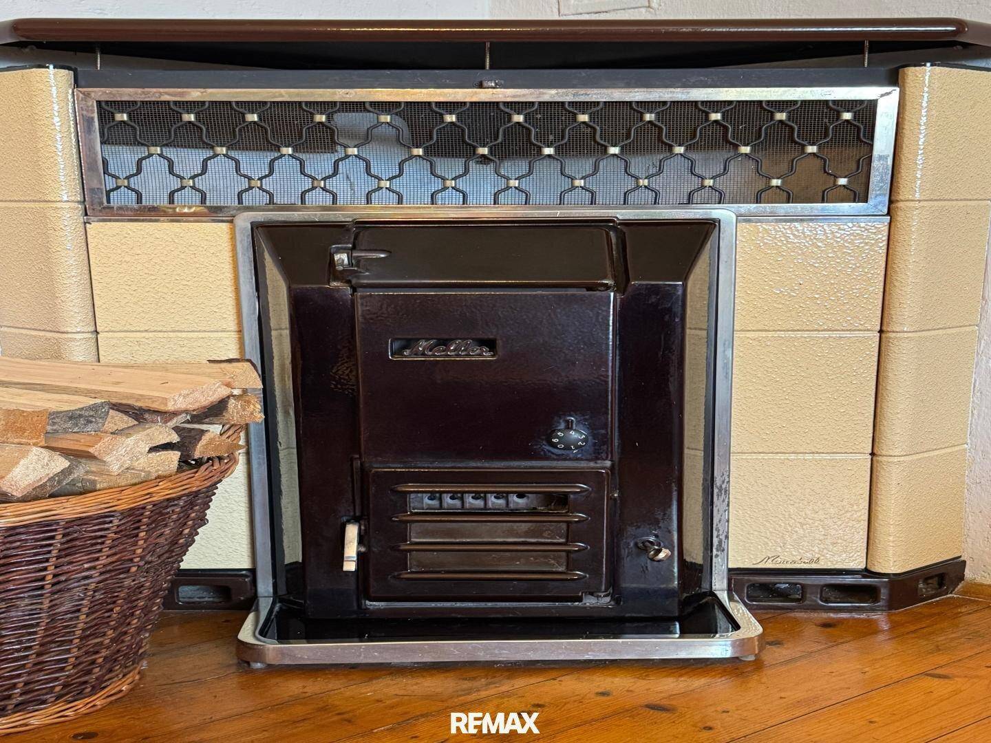 Detailansicht eines traditionellen Kaminofens mit Holzkorb, der Wärme und Gemütlichkeit spendet.