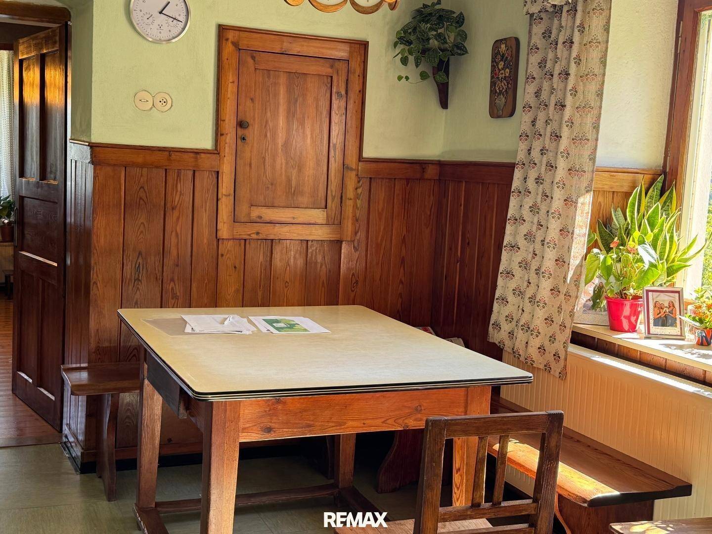 Gemütlicher Essbereich mit Holztisch, Bänken und traditioneller Holzvertäfelung an den Wänden.
