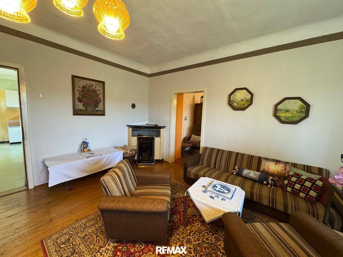 Wohnzimmer mit Holzboden, gemütlicher Sitzecke und einem traditionellen Kaminofen.