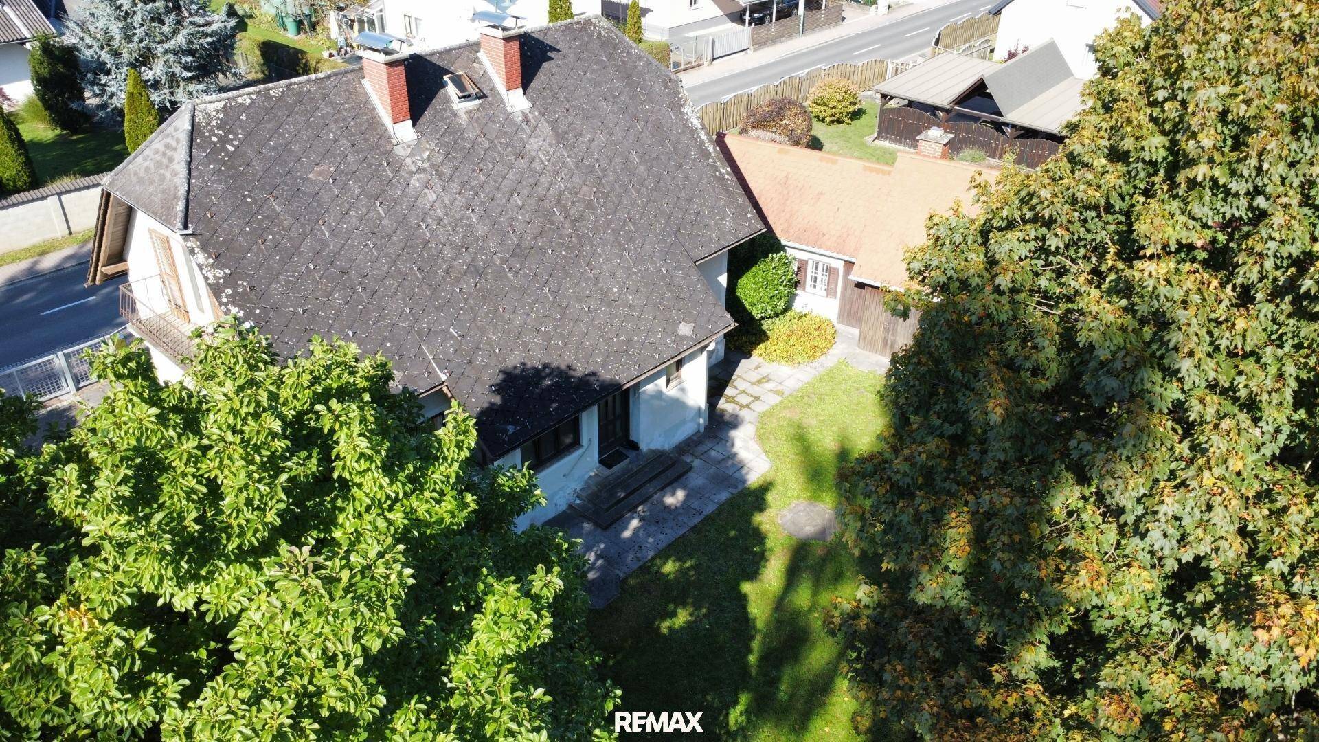 Vogelperspektive des Hauses mit Satteldach, umgeben von üppigem Grün und Bäumen.