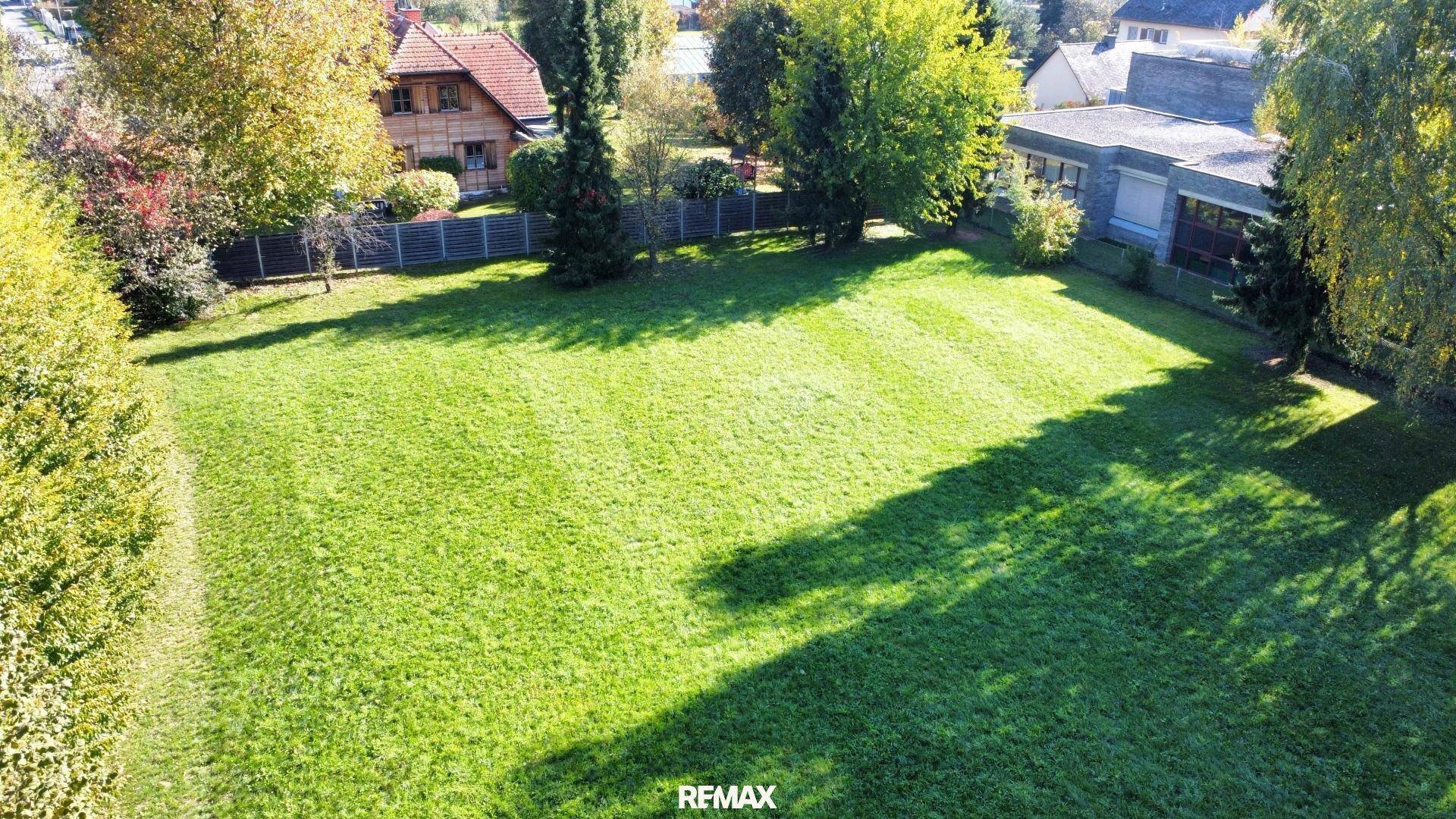 Luftaufnahme eines weitläufigen, gepflegten Gartens mit viel Grünfläche und Bäumen.