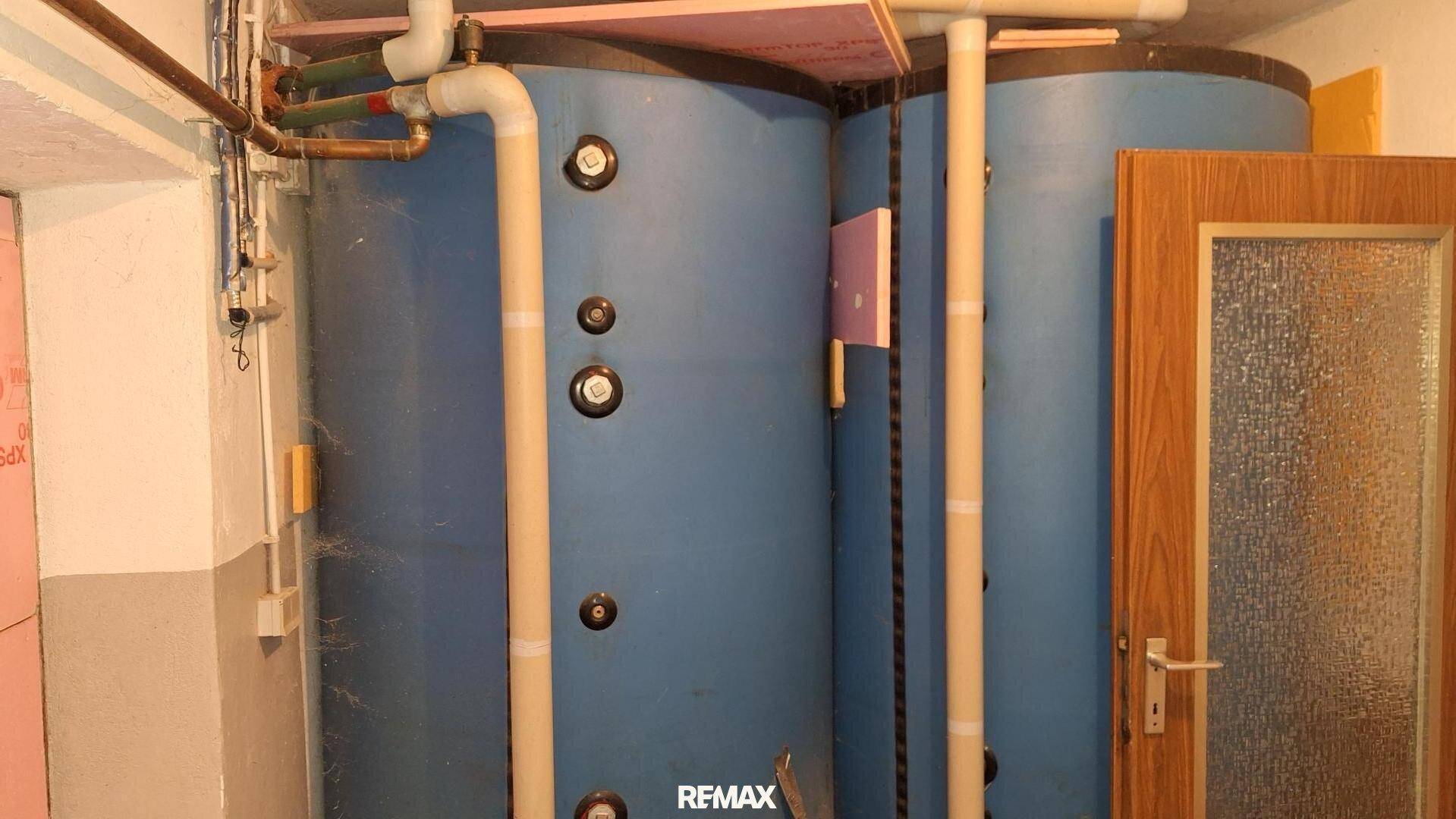 Heizraum mit zwei großen blauen Wassertanks und sichtbaren Rohren.