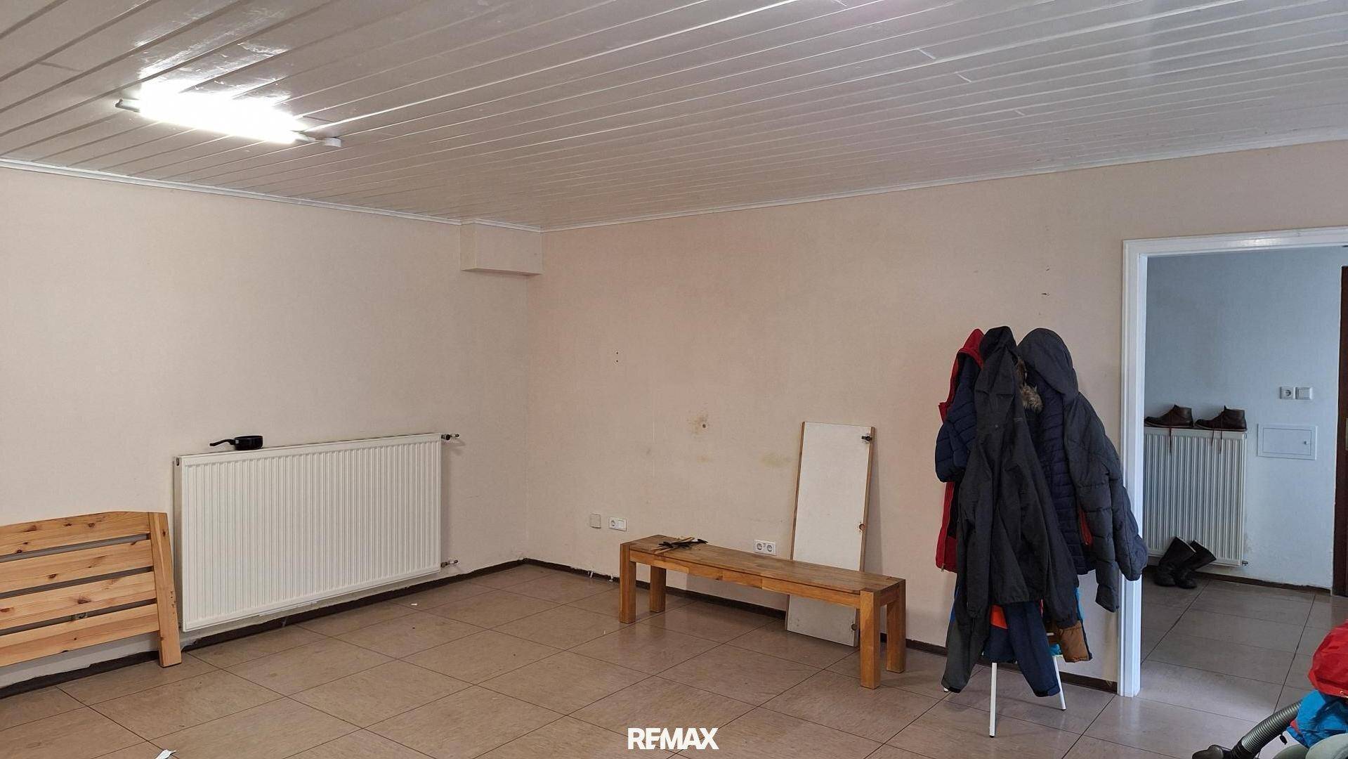 Heller Raum mit Fliesenboden, Heizkörper und Holzdecke, bereit zur individuellen Gestaltung.