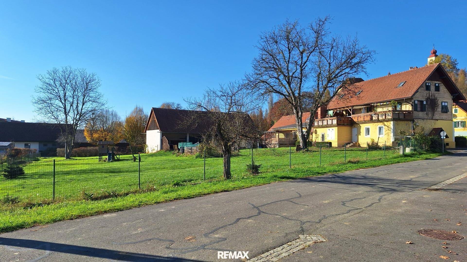 Weitläufiges Grundstück mit gelbem Haus, Scheune und kahlen Bäumen unter klarem Himmel.