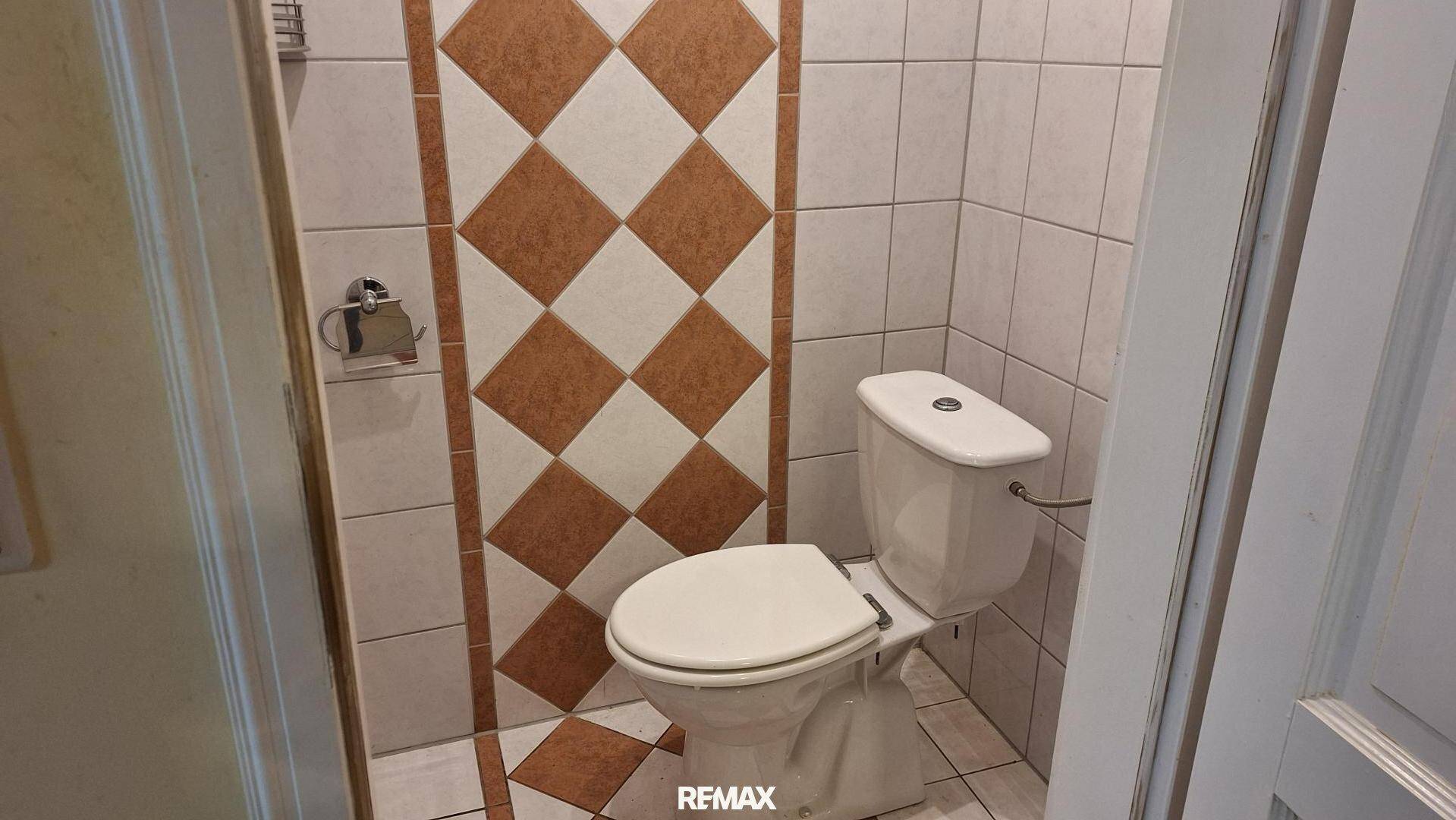 Kleines WC mit Steh-WC und gemusterten Wandfliesen in Braun- und Beigetönen.