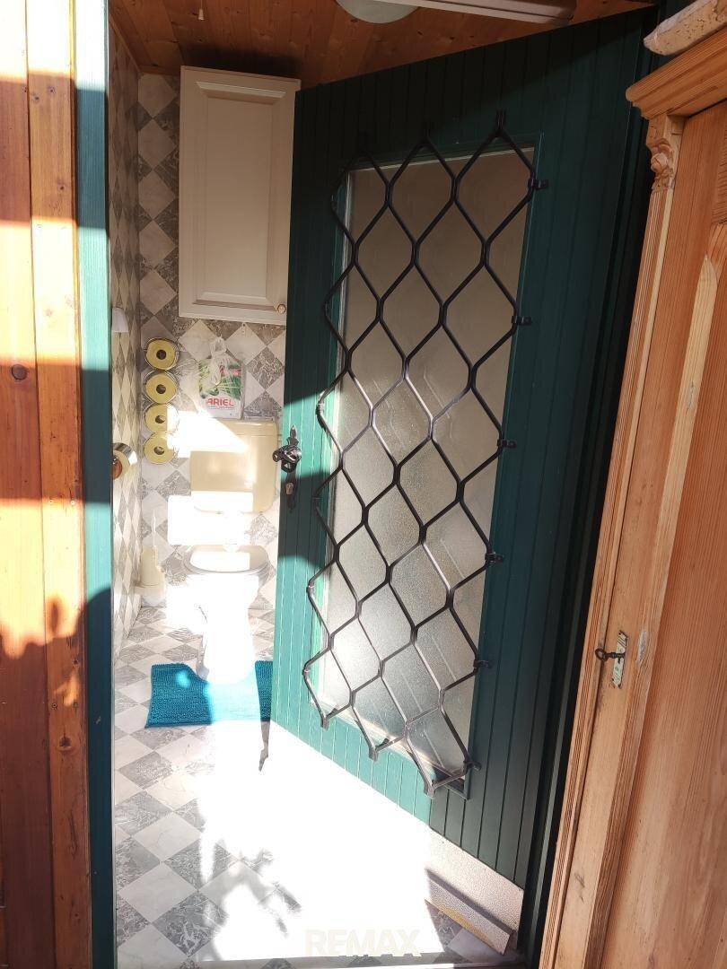 Separater WC-Bereich mit gemusterten Fliesen und natürlichem Lichteinfall durch die Tür.