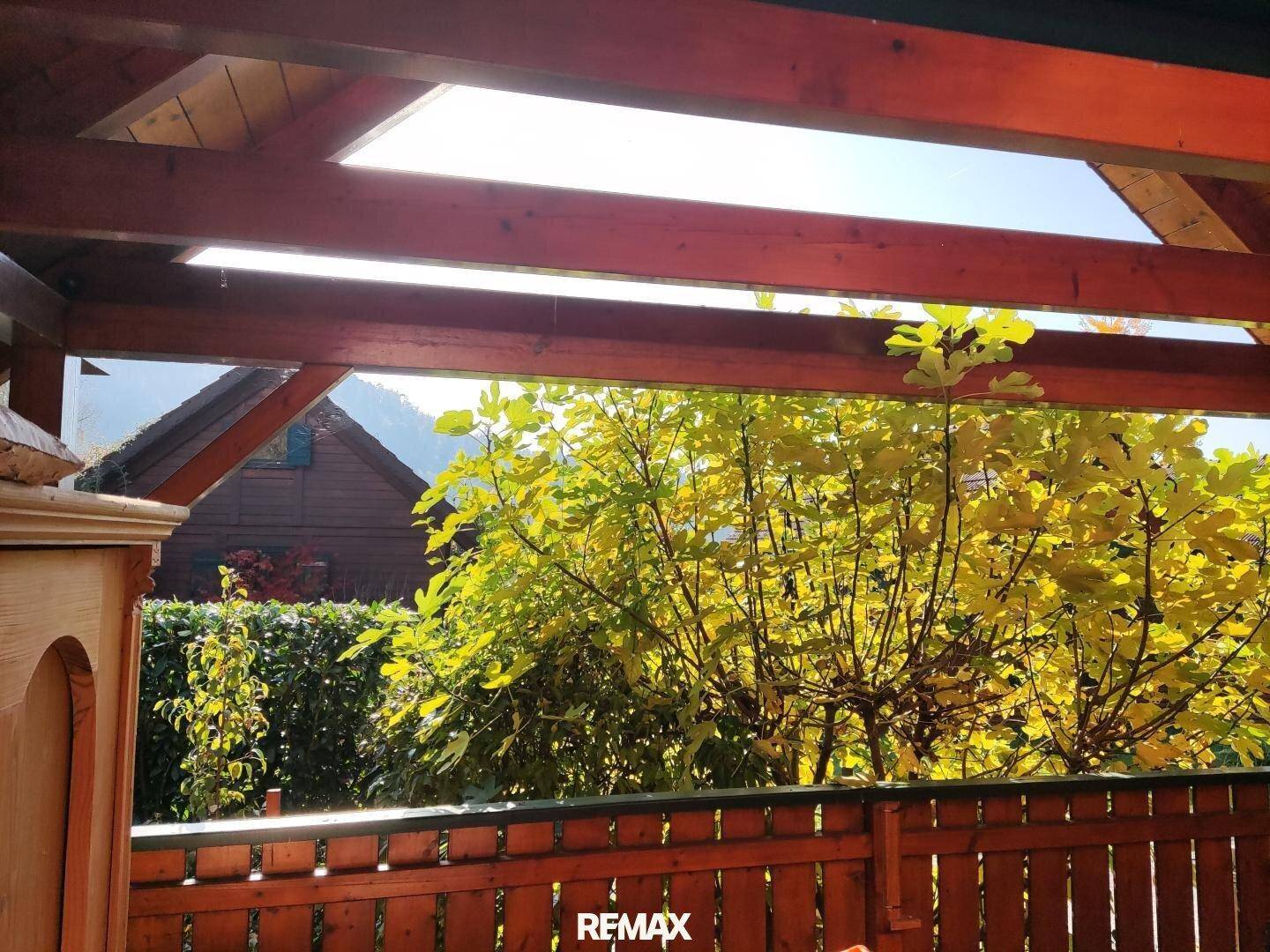 Blick vom überdachten Holzbalkon auf die umliegende Natur und ein weiteres Holzhaus im Hintergrund.