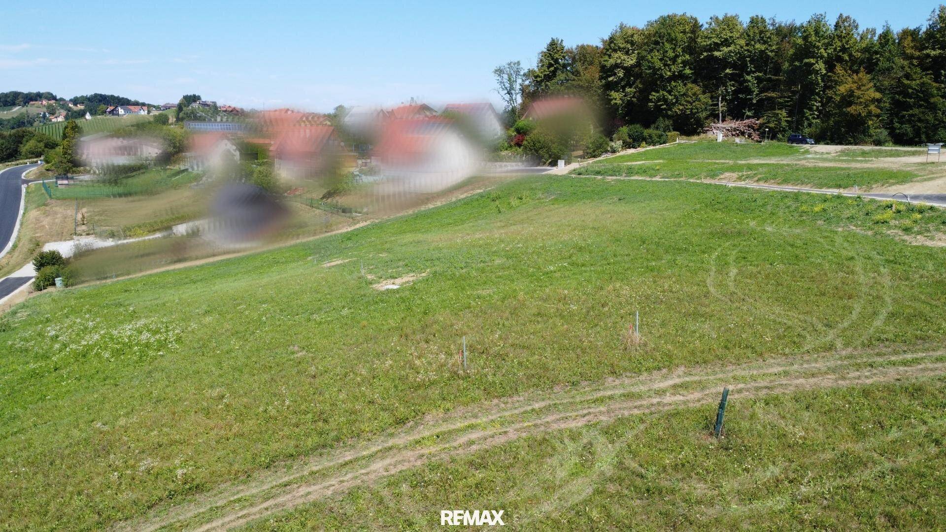 Grünes Hanggrundstück mit Blick auf die umliegende Landschaft und eine Zufahrtsstraße.