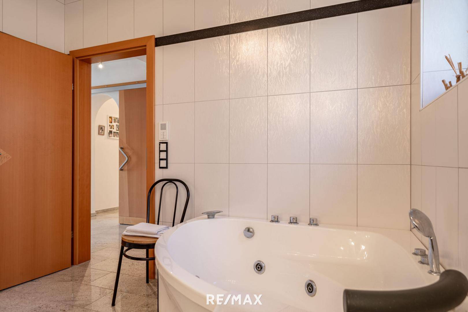 Geräumiges Badezimmer mit einer luxuriösen Eck-Whirlpool-Badewanne und hellen Fliesen.