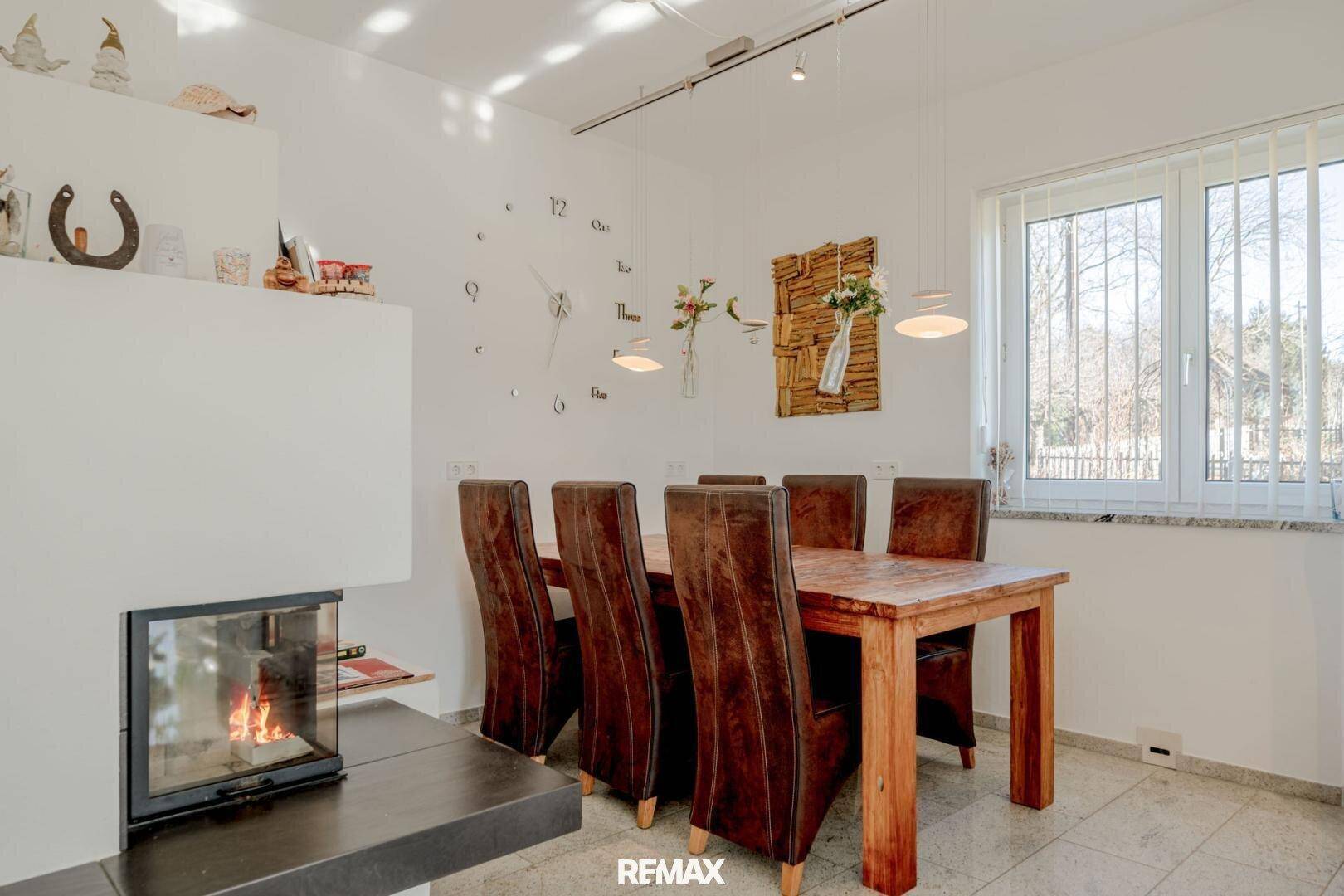 Gemütlicher Essbereich mit Holztisch, Lederstühlen und modernem Kamin für warme Abende.