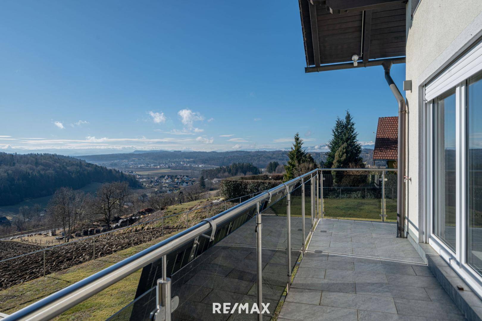 Großer Balkon mit Glasgeländer und weitem Blick über die umliegende Landschaft.