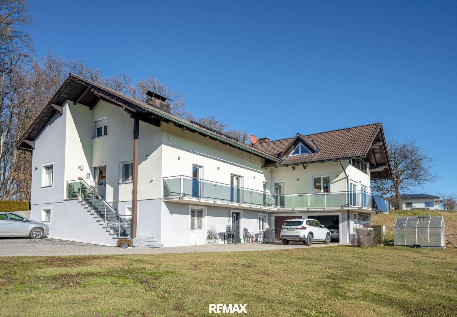 Großzügiges Einfamilienhaus mit mehreren Balkonen und integrierter Garage in ländlicher Umgebung.