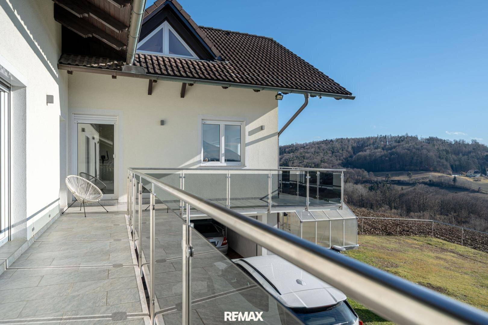 Langer Balkon mit Glasgeländer und weitem Blick über die hügelige Landschaft.
