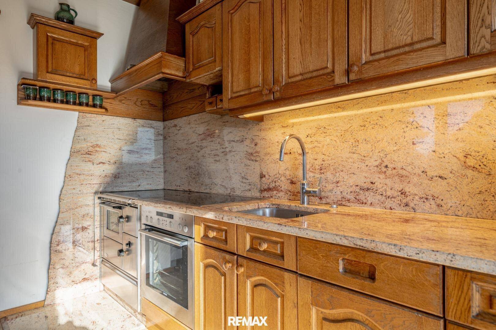Rustikale Küche mit Holzschränken, Granit-Arbeitsplatte und integrierten Geräten.