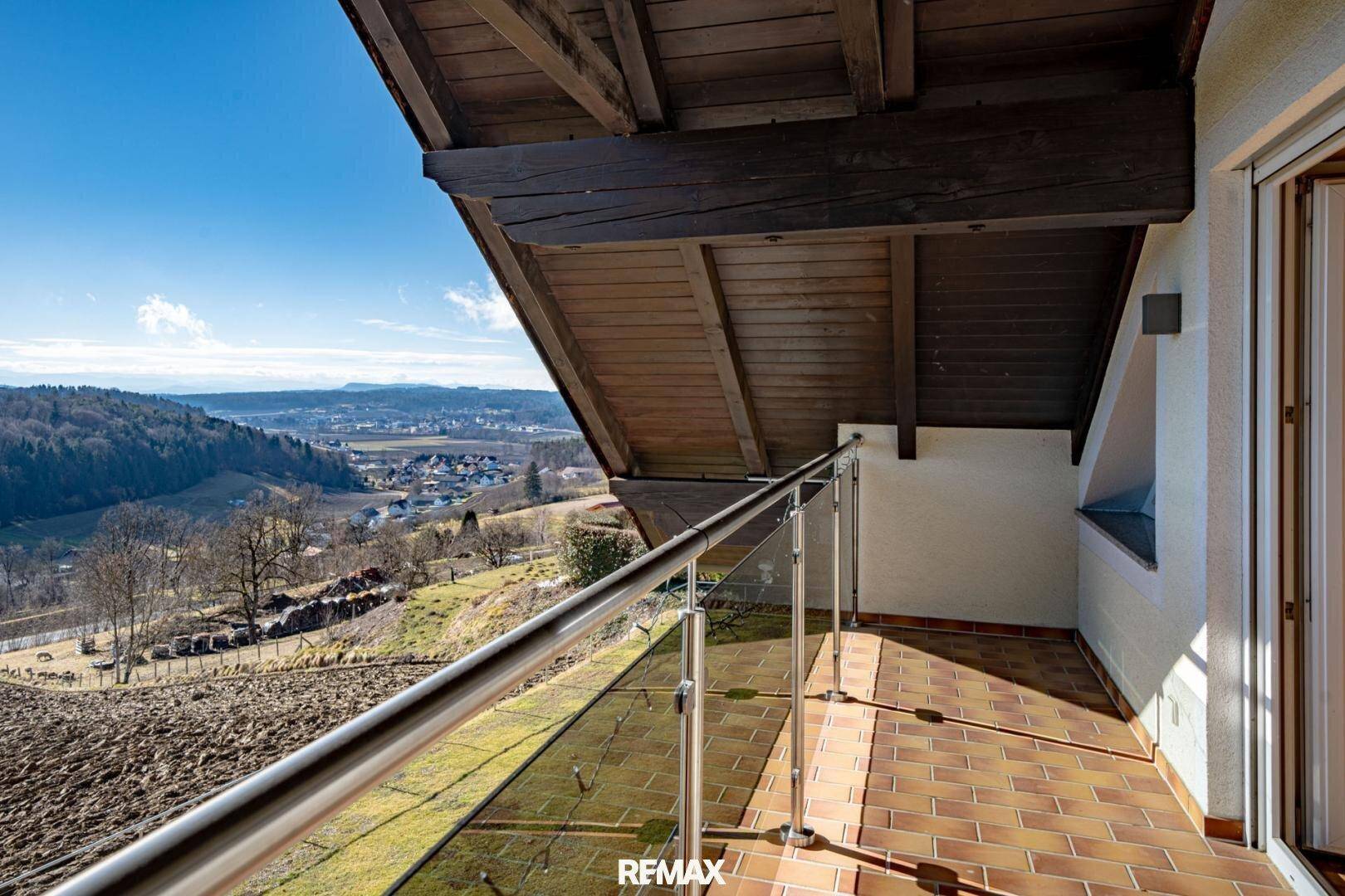 Überdachter Balkon im Dachgeschoss mit Ziegelboden und weitem Blick über die Landschaft.