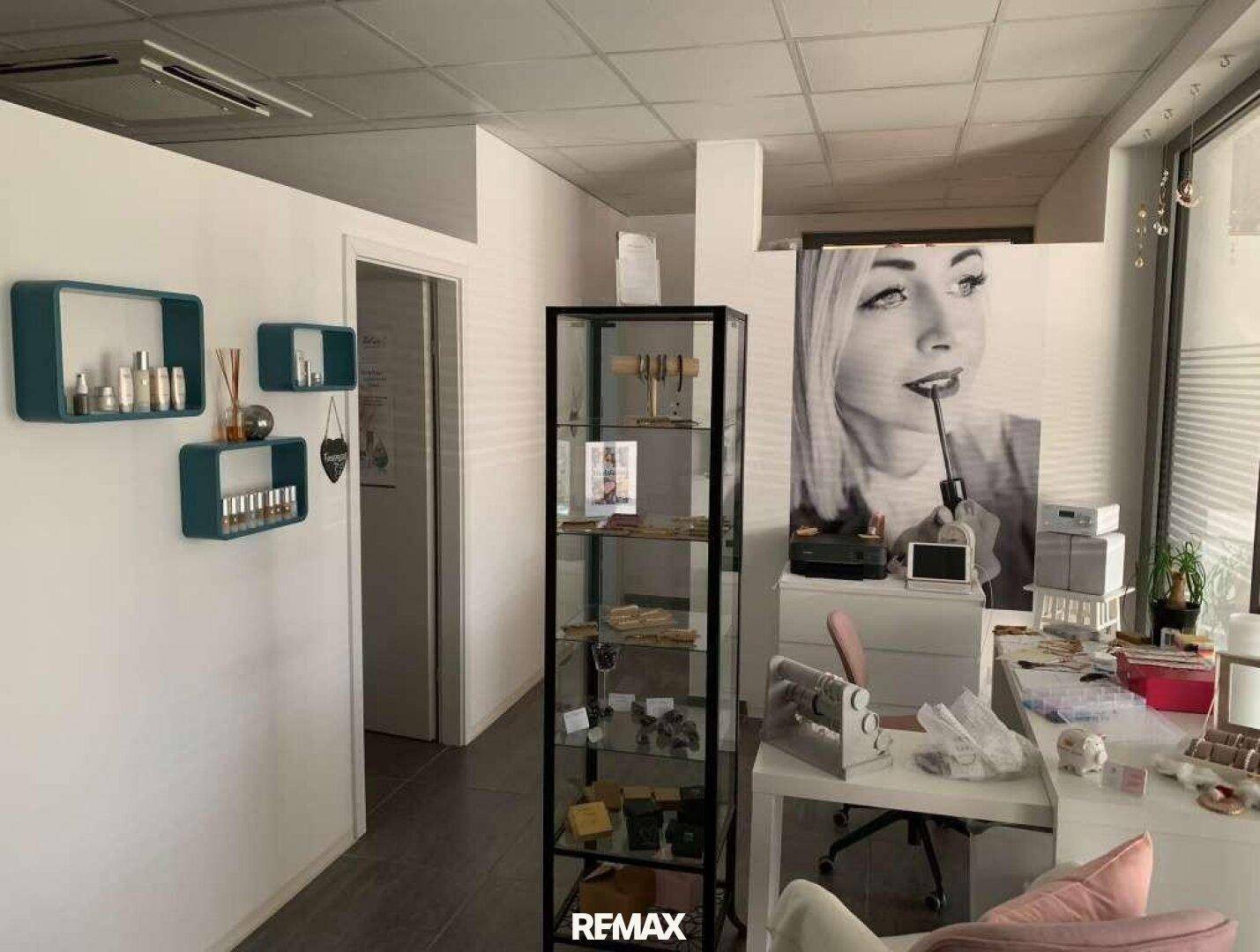 Innenansicht eines Verkaufsraums mit einer Glasvitrine, Regalen und einem Schreibtisch.