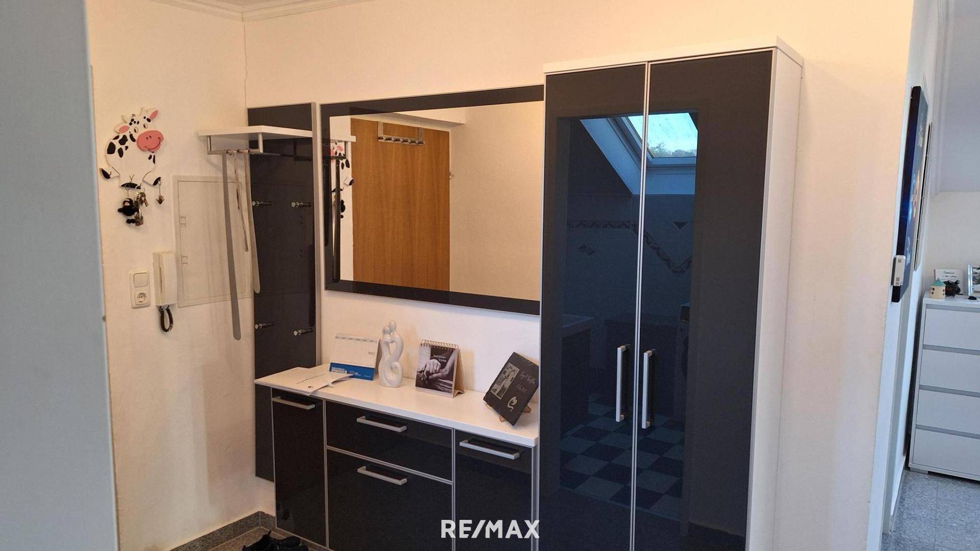 Moderner Eingangsbereich mit großem Spiegel, Garderobe und praktischen Schränken.