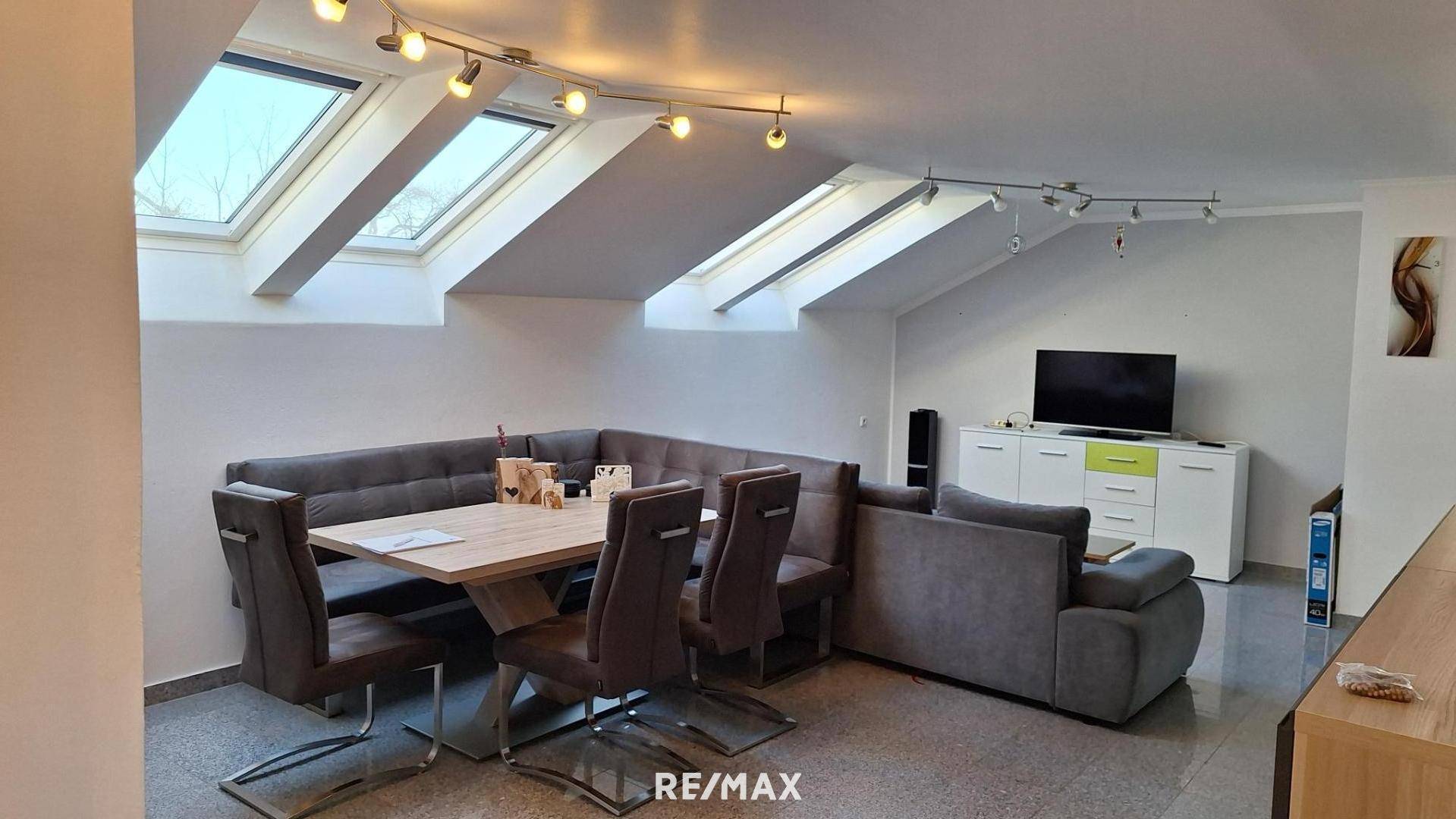 Heller Wohn- und Essbereich im Dachgeschoss mit gemütlicher Eckbank, Sofa und Dachfenstern.