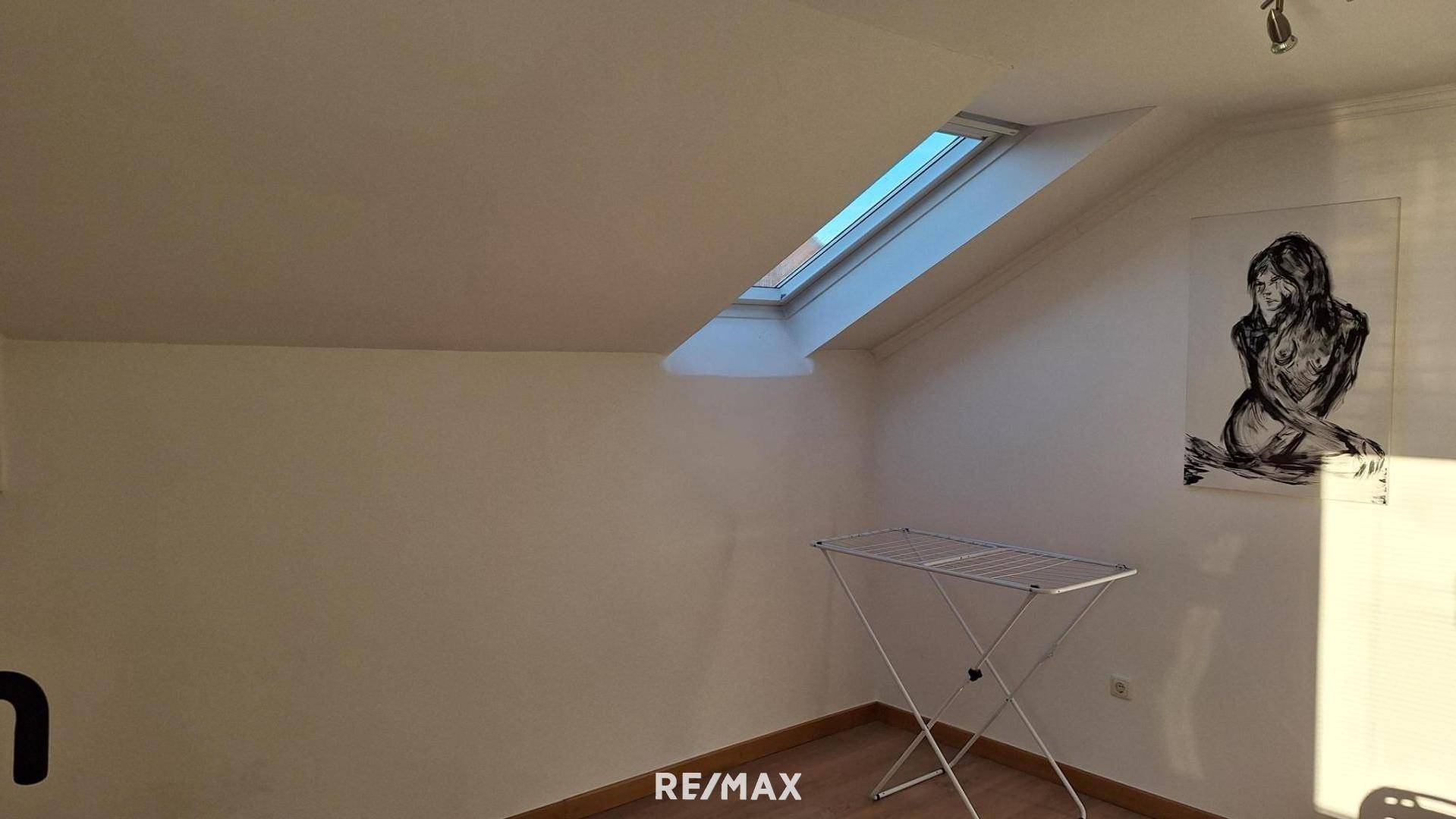 Heller Raum im Dachgeschoss mit Dachfenster und Wäscheständer, vielseitig nutzbar.