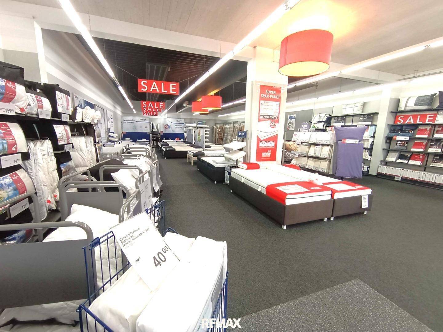 Geräumiger Verkaufsraum mit Betten, Matratzen und weiteren Produkten auf Regalen.