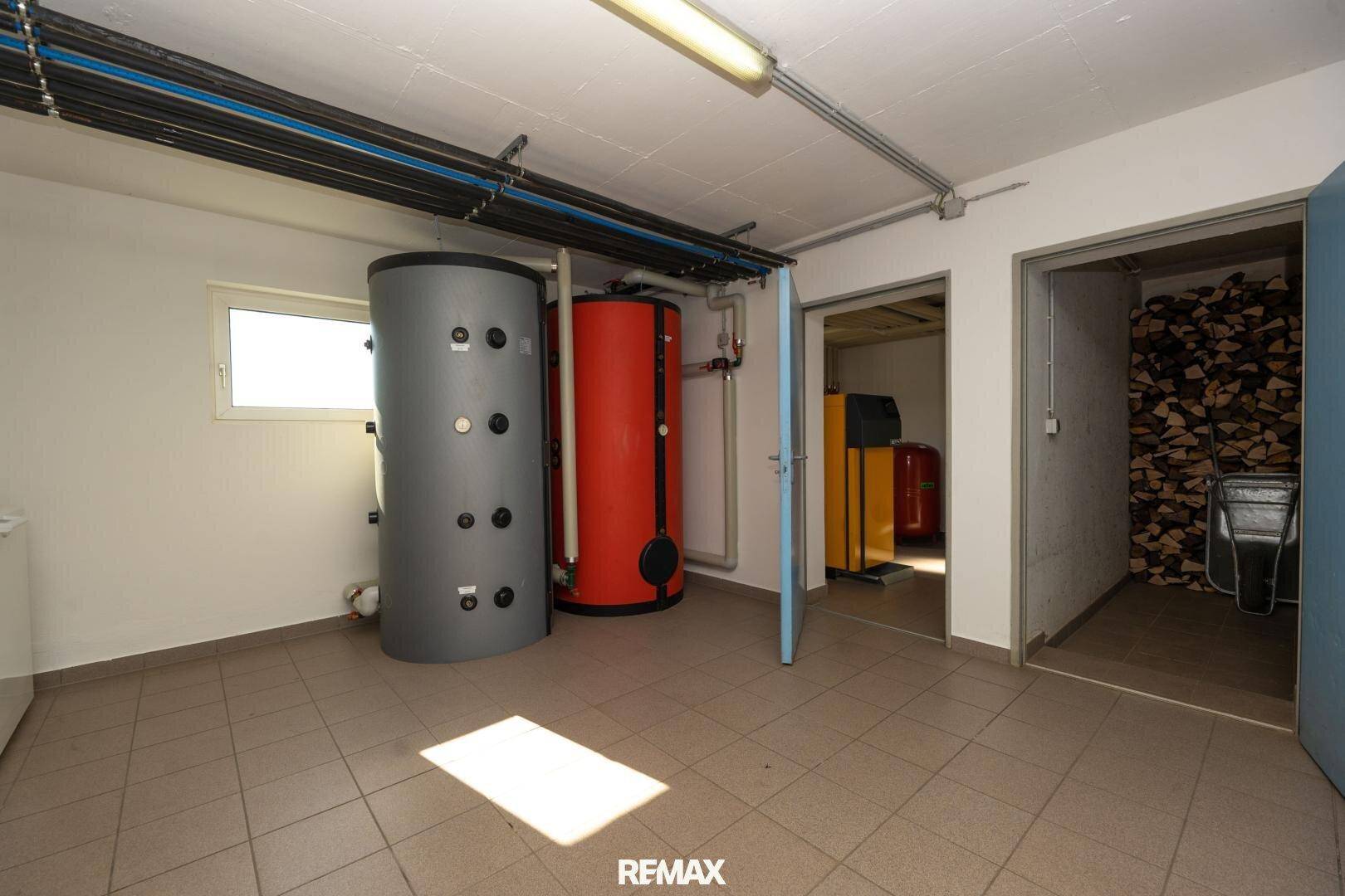 Geräumiger Kellerraum mit Heizungsanlagen und Zugang zu einem Holzlageraum.