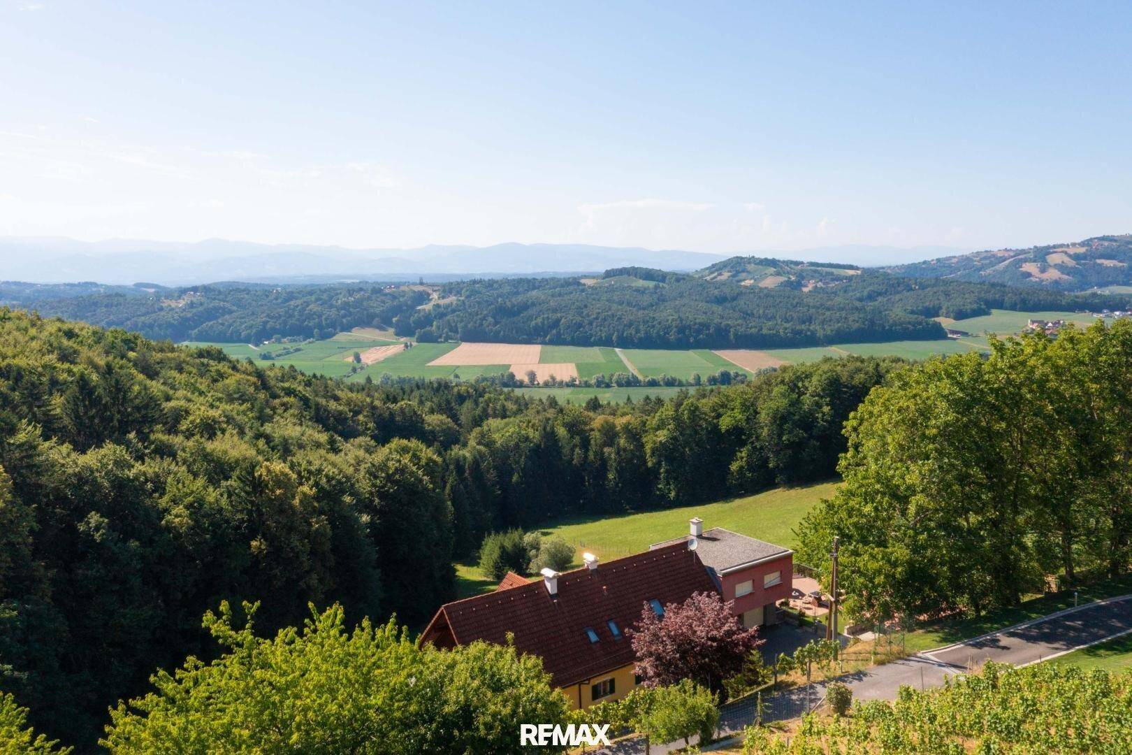 Panoramablick auf das Anwesen und die weite, grüne Landschaft mit Feldern und Wäldern.