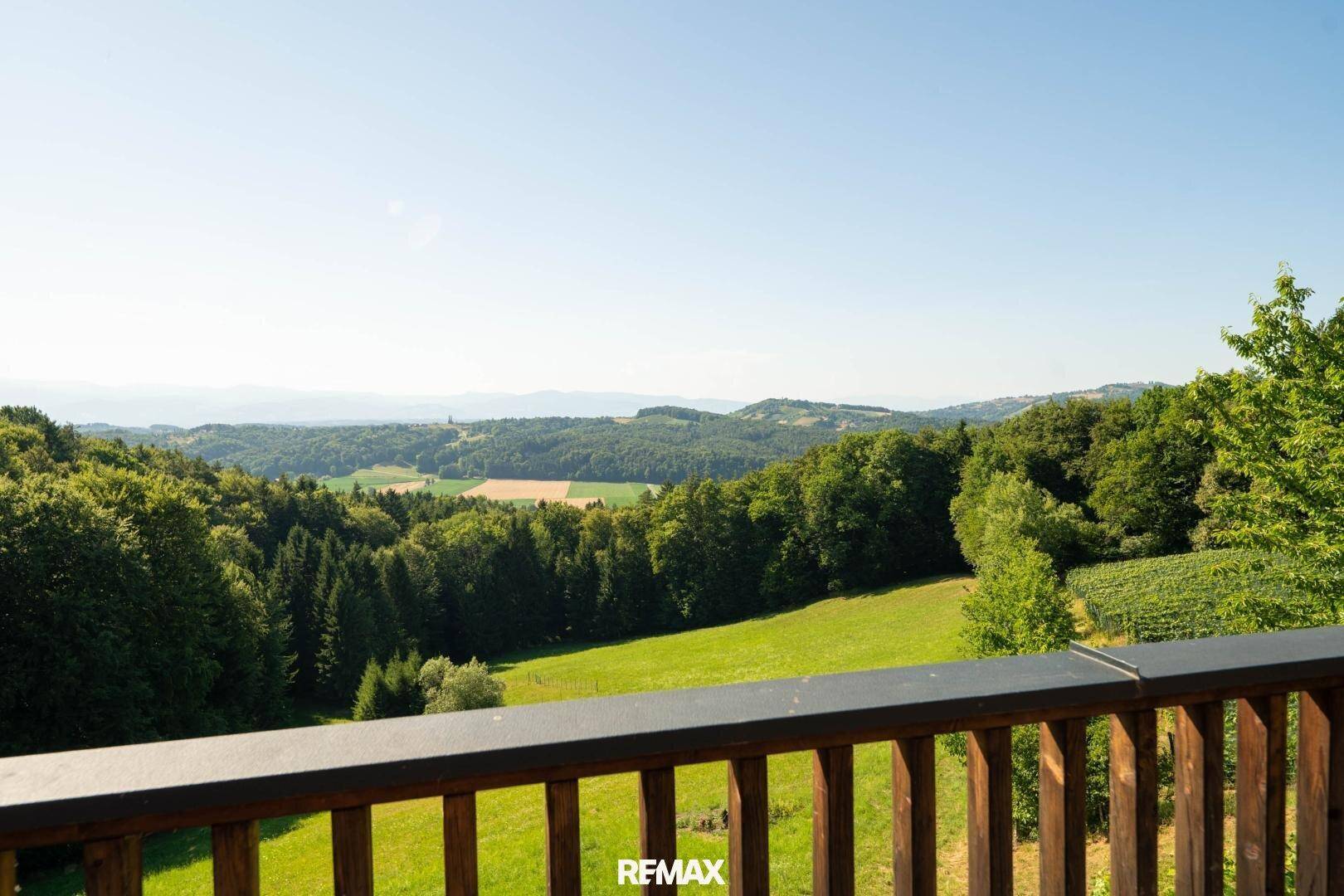 Weitläufiger Panoramablick über die grüne Hügellandschaft mit Wäldern und Feldern.