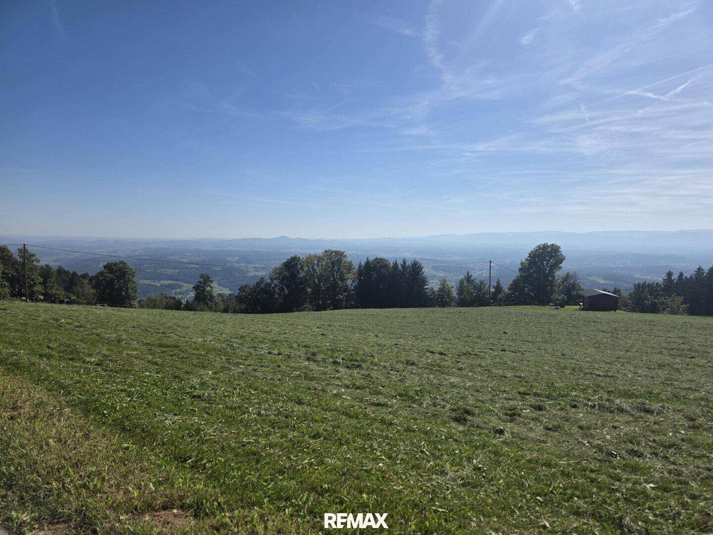 Weitläufige Wiesenlandschaft mit Panoramablick auf die umliegenden Berge und den Horizont.