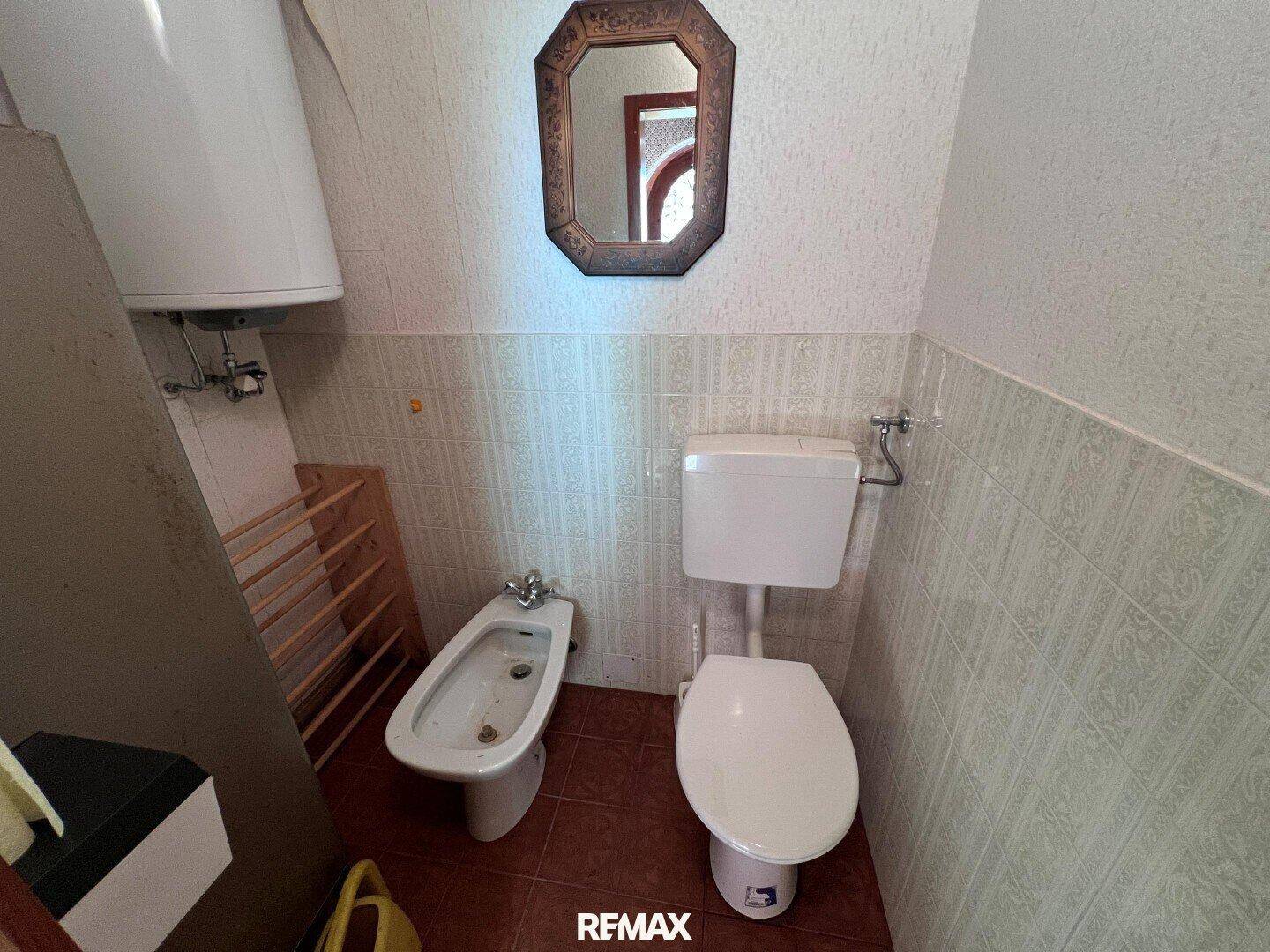 Separates WC mit Toilette, Bidet und Spiegel, einfach und funktional ausgestattet.