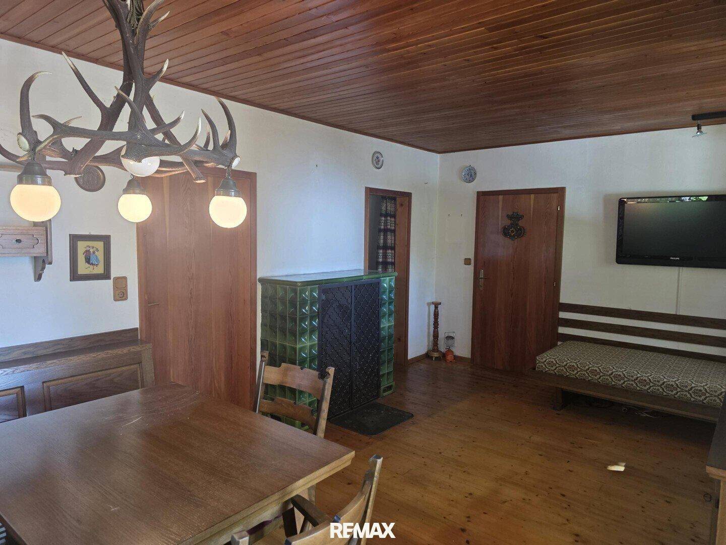 Rustikaler Wohn-Essbereich mit Kachelofen, Holzboden und Holzdecke, im traditionellen Stil.